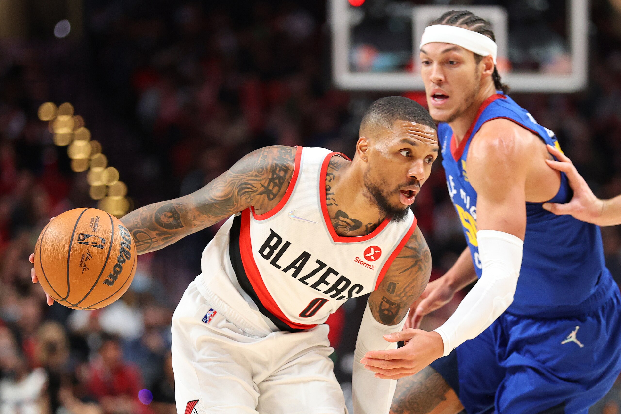 PORTLAND, OREGON - NOVEMBER 23: Damian Lillard #0 of the Portland Trail Blazers works towards the basket against Aaron Gordon #50 of the Denver Nuggets during the first half at Moda Center on November 23, 2021 in Portland, Oregon. NOTE TO USER: User expressly acknowledges and agrees that, by downloading and or using this photograph, User is consenting to the terms and conditions of the Getty Images License Agreement.  (Photo by Abbie Parr/Getty Images)