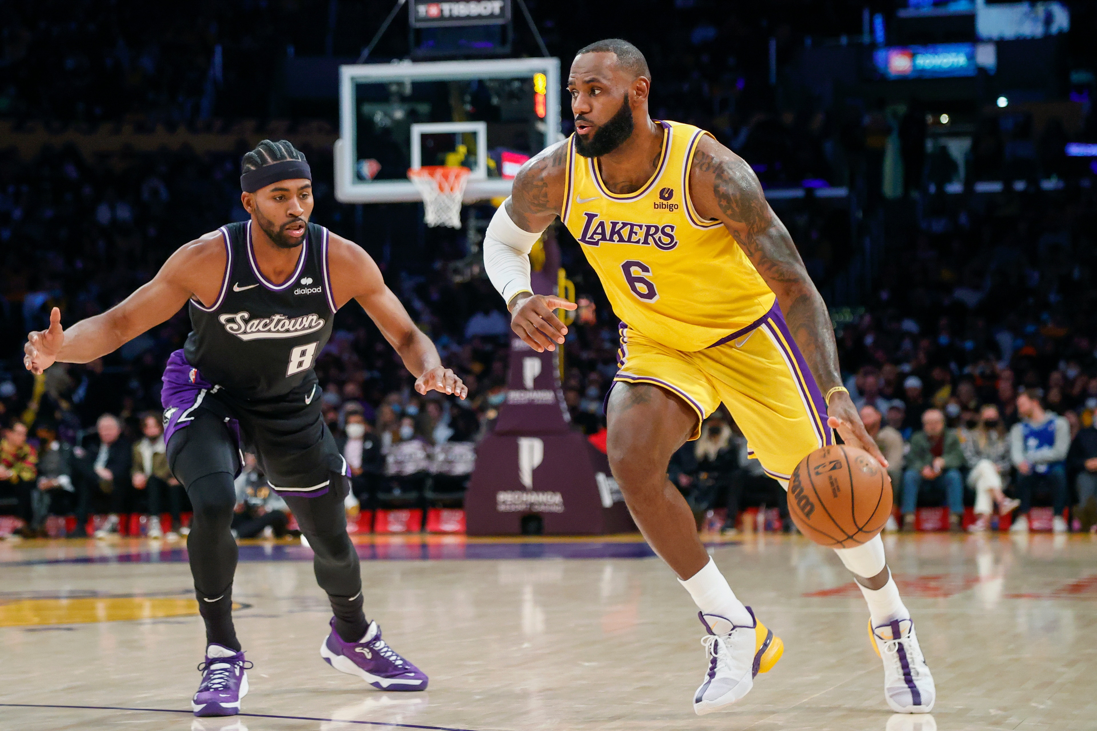 LeBron James, de los Lakers de Los Ángeles, avanza ante su rival de los Kings de Sacramento Maurice Harkless (8) en la primera mitad del juego de la NBA que enfrentó a ambos equipos, en Los Ángeles, el 26 de noviembre de 2021. (AP Foto/Ringo H.W. Chiu)