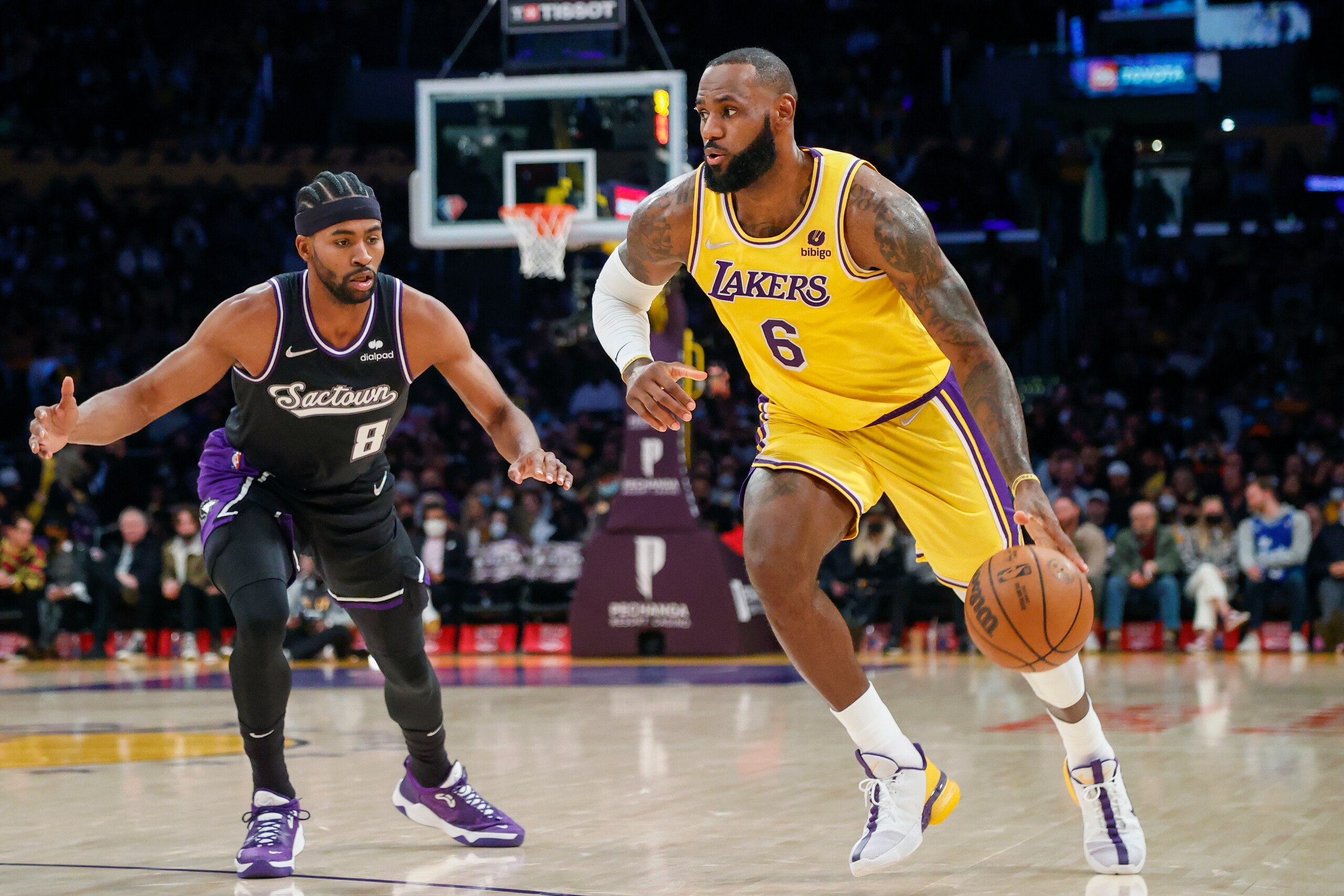 LeBron James, de los Lakers de Los Ángeles, avanza ante su rival de los Kings de Sacramento Maurice Harkless (8) en la primera mitad del juego de la NBA que enfrentó a ambos equipos, en Los Ángeles, el 26 de noviembre de 2021. (AP Foto/Ringo H.W. Chiu)