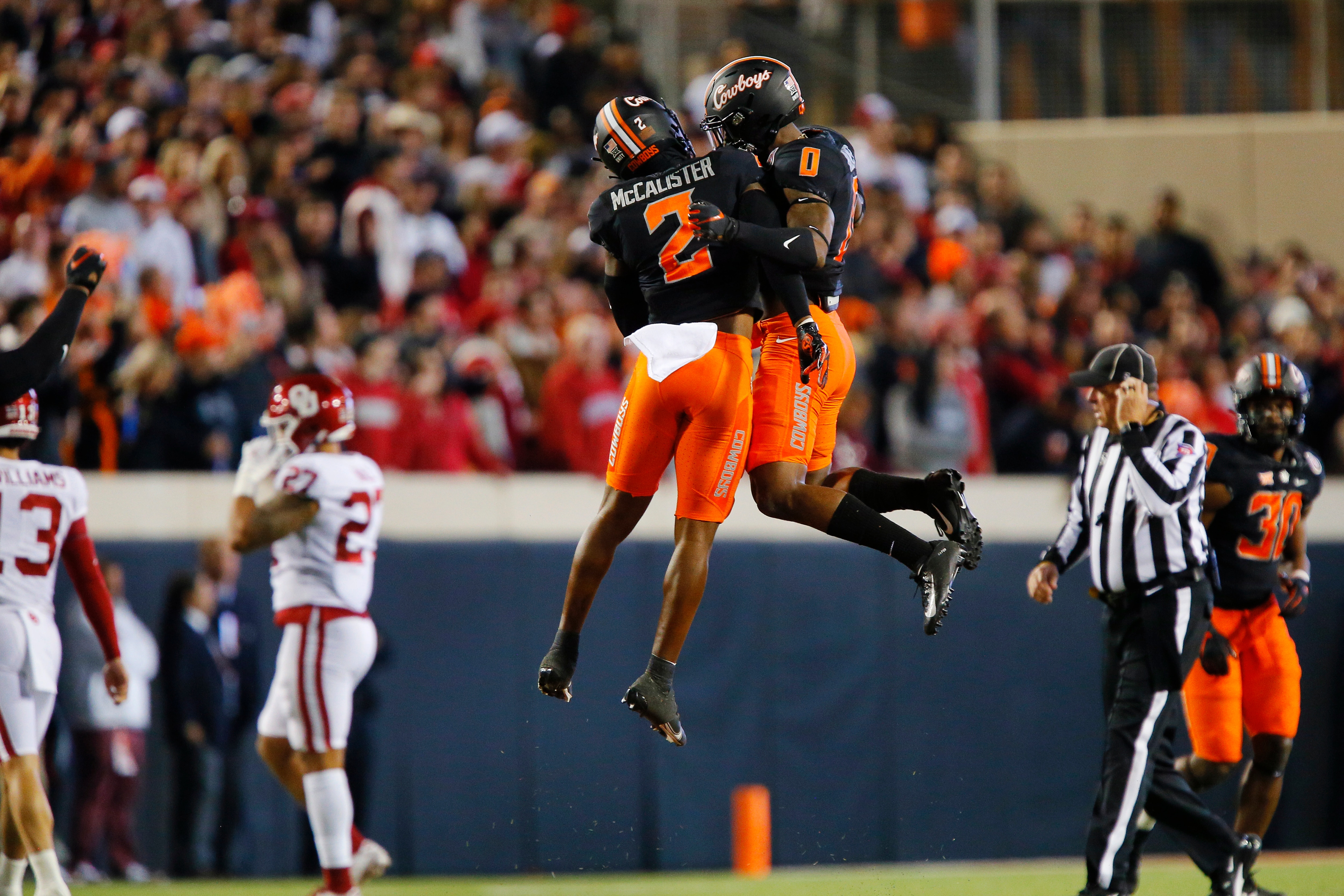 STILLWATER, OK - NOVEMBER 27:  Safety Tanner McCalister #2 and cornerback Christian Holmes #0 of the Oklahoma State Cowboys celebrate after stopping a drive by the Oklahoma Sooners in the first quarter at Boone Pickens Stadium on November 27, 2021 in Stillwater, Oklahoma.  (Photo by Brian Bahr/Getty Images)
