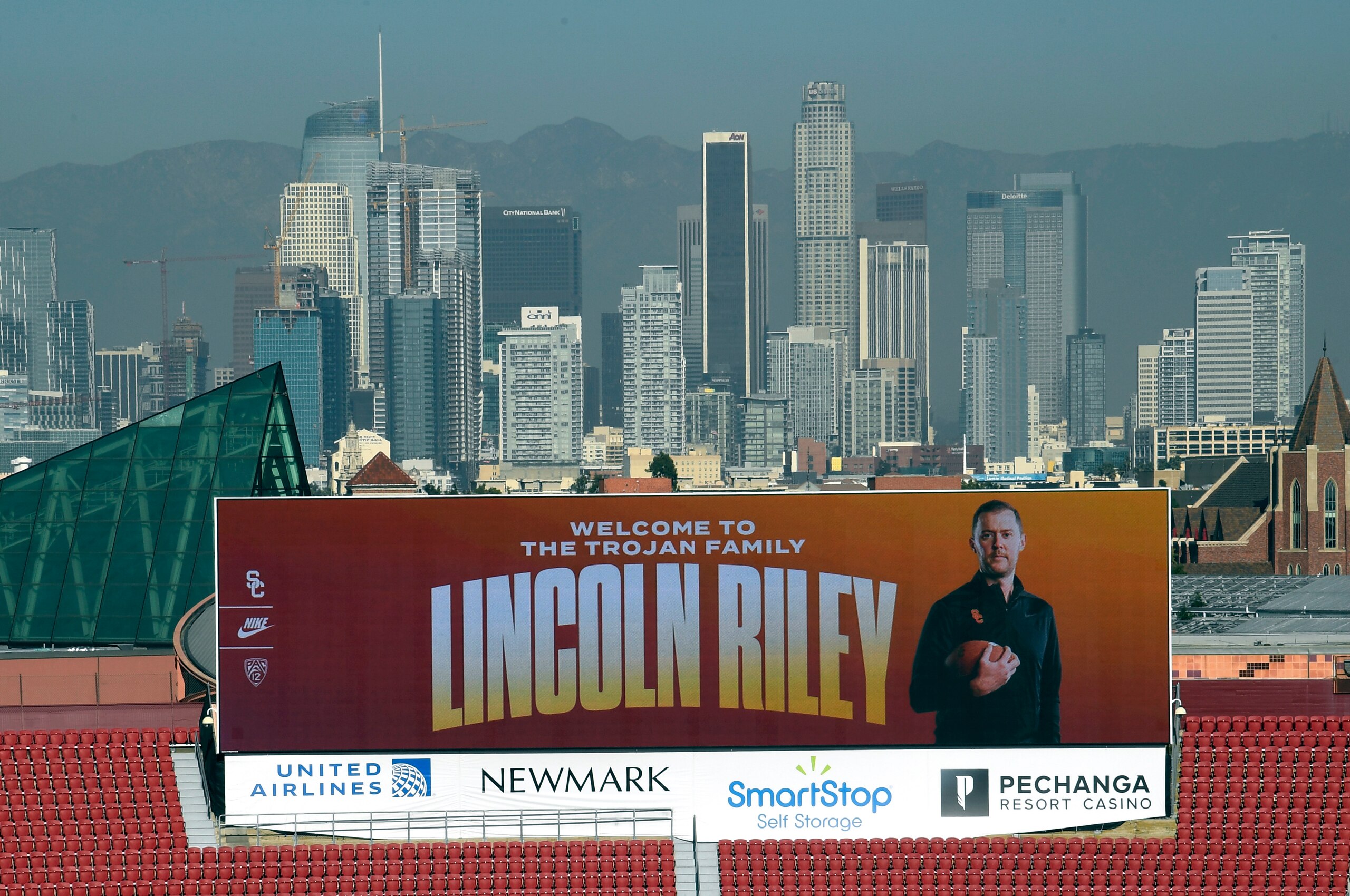 LOS ANGELES, CA - NOVEMBER 29: A large screen at the Los Angeles Coliseum display a photo of the new USC football head coach Lincoln Riley, with downtown Los Angeles as the background, before he is introduced by university president Carol L. Folt and athletic director Mike Bohn in the 1923 Club at the Los Angeles Coliseum on November 29, 2021 in Los Angeles, California. (Photo by Kevork Djansezian/Getty Images) LOS ANGELES, CA - NOVEMBER 29: A large screen at the Los Angeles Coliseum display a photo of the new USC football head coach Lincoln Riley, with downtown Los Angeles as the background, before he is introduced by university president Carol L. Folt and athletic director Mike Bohn in the 1923 Club at the Los Angeles Coliseum on November 29, 2021 in Los Angeles, California. (Photo by Kevork Djansezian/Getty Images)