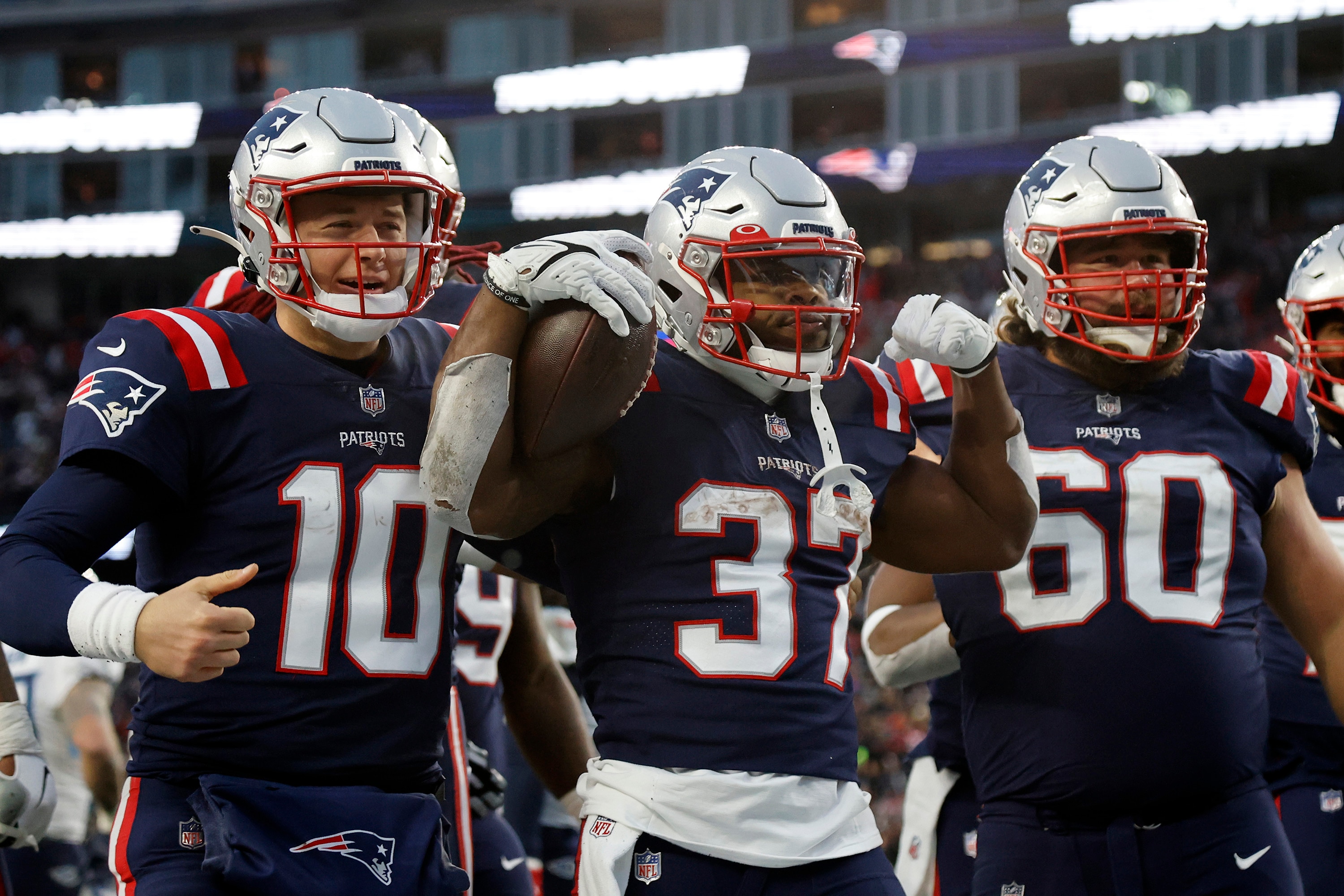 New England Patriots running back Damien Harris (37) celebrates after scoring a touchdown with teammates Mac Jones (10) and David Andrews (60) during the second half of an NFL football game against the Tennessee Titans, Sunday, Nov. 28, 2021, in Foxborough, Mass. (AP Photo/Mary Schwalm)