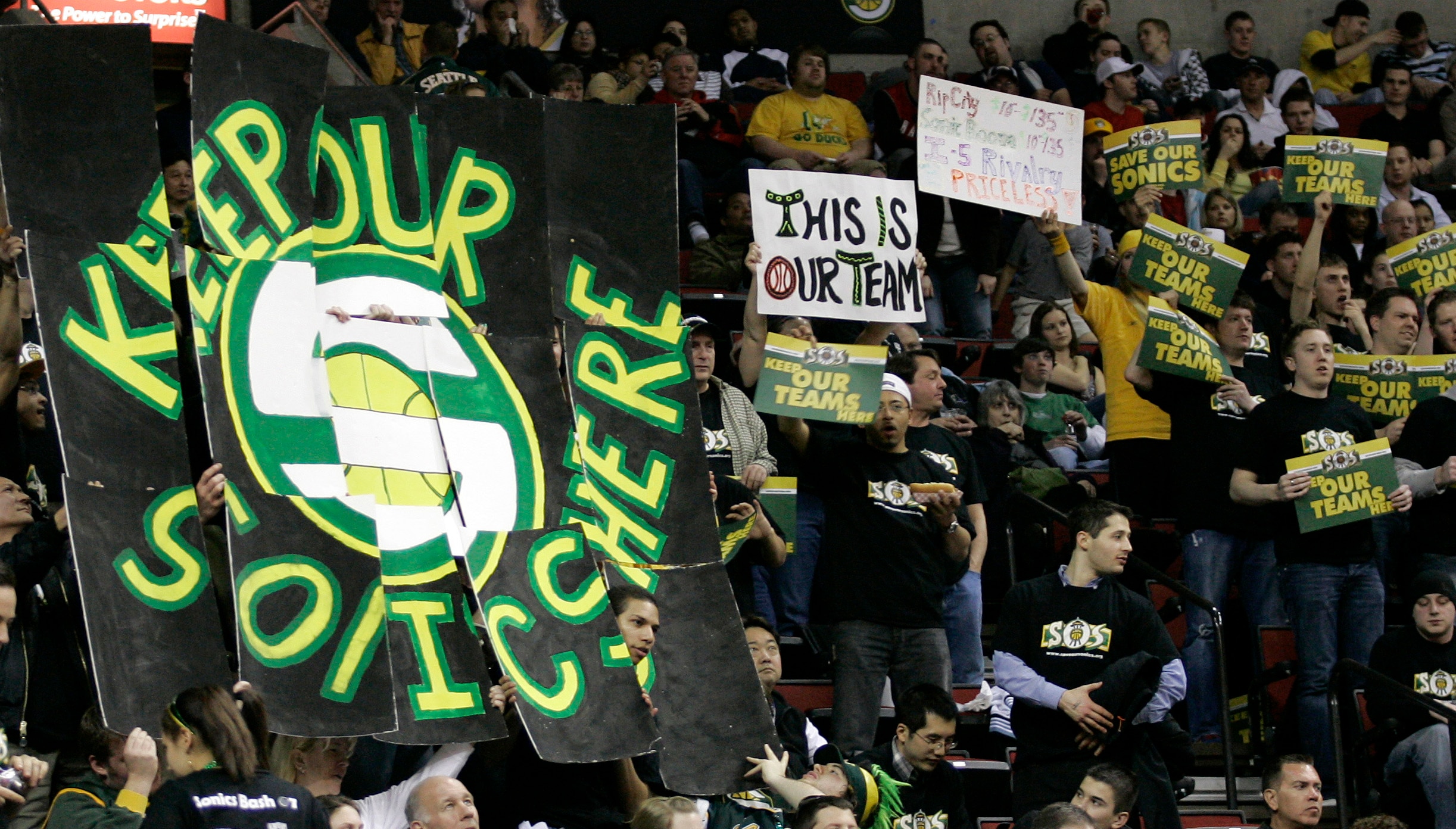 FILE - In this March 24, 2008 file phoito, Seattle SuperSonics fans hold signs in favor of keeping the NBA basketball team in Seattle during an NBA basketball game against the Portland Trail Blazers at KeyArena in Seattle. KeyArena is getting an appropriate send off Friday, Oct. 5, 2018, with an NBA game being played once again under its roof as the former home of the SuperSonics will see the Golden State Warriors meet the Sacramento Kings in a preseason game. Afterward, the building will be shuttered and remodeled. (AP Photo/Ted S. Warren, File)