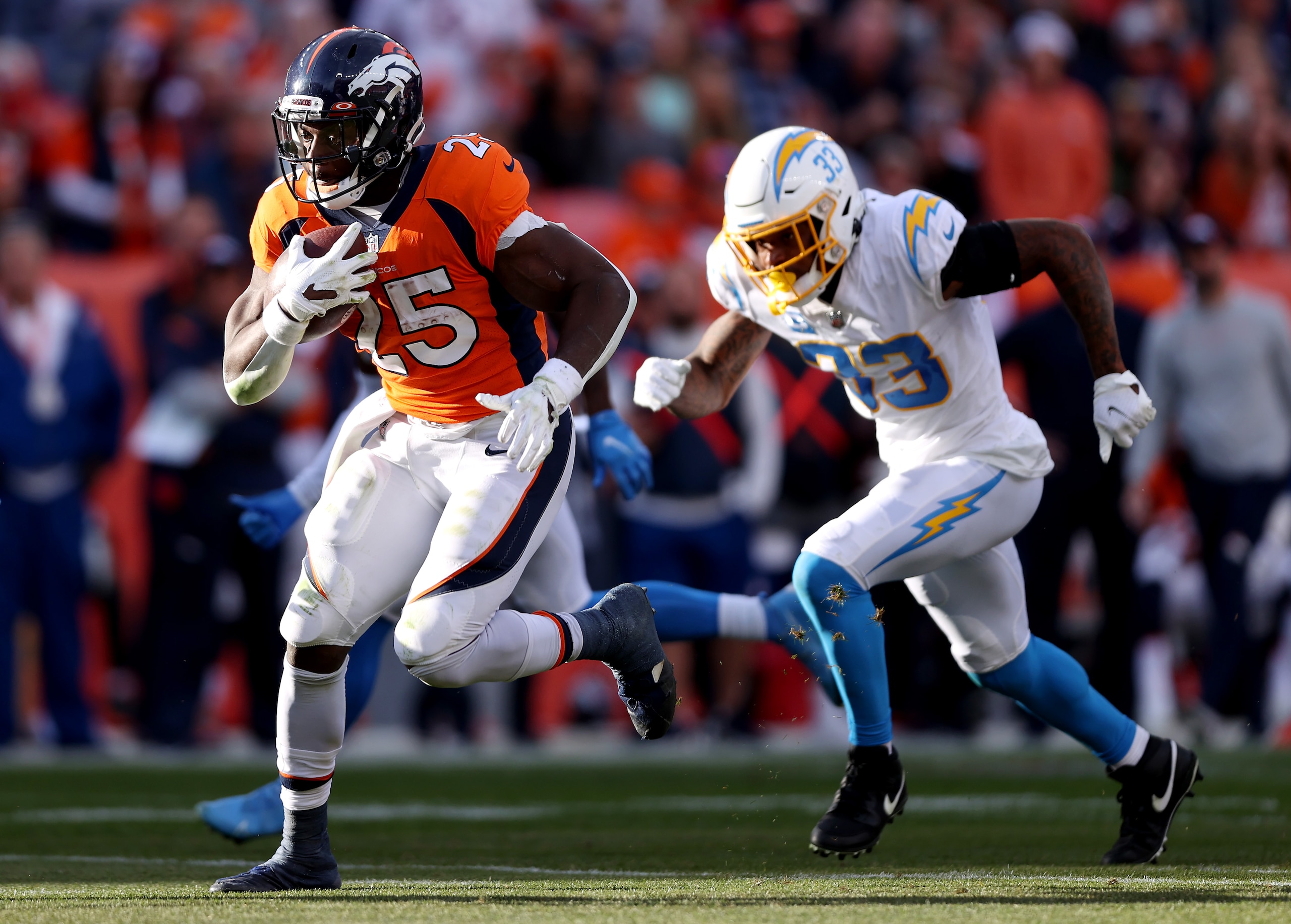 DENVER, COLORADO - NOVEMBER 28: Melvin Gordon #25 of the Denver Broncos carries the ball as Derwin James #33 of the Los Angeles Chargers defends in the second half of the game at Empower Field At Mile High on November 28, 2021 in Denver, Colorado. (Photo by Matthew Stockman/Getty Images)