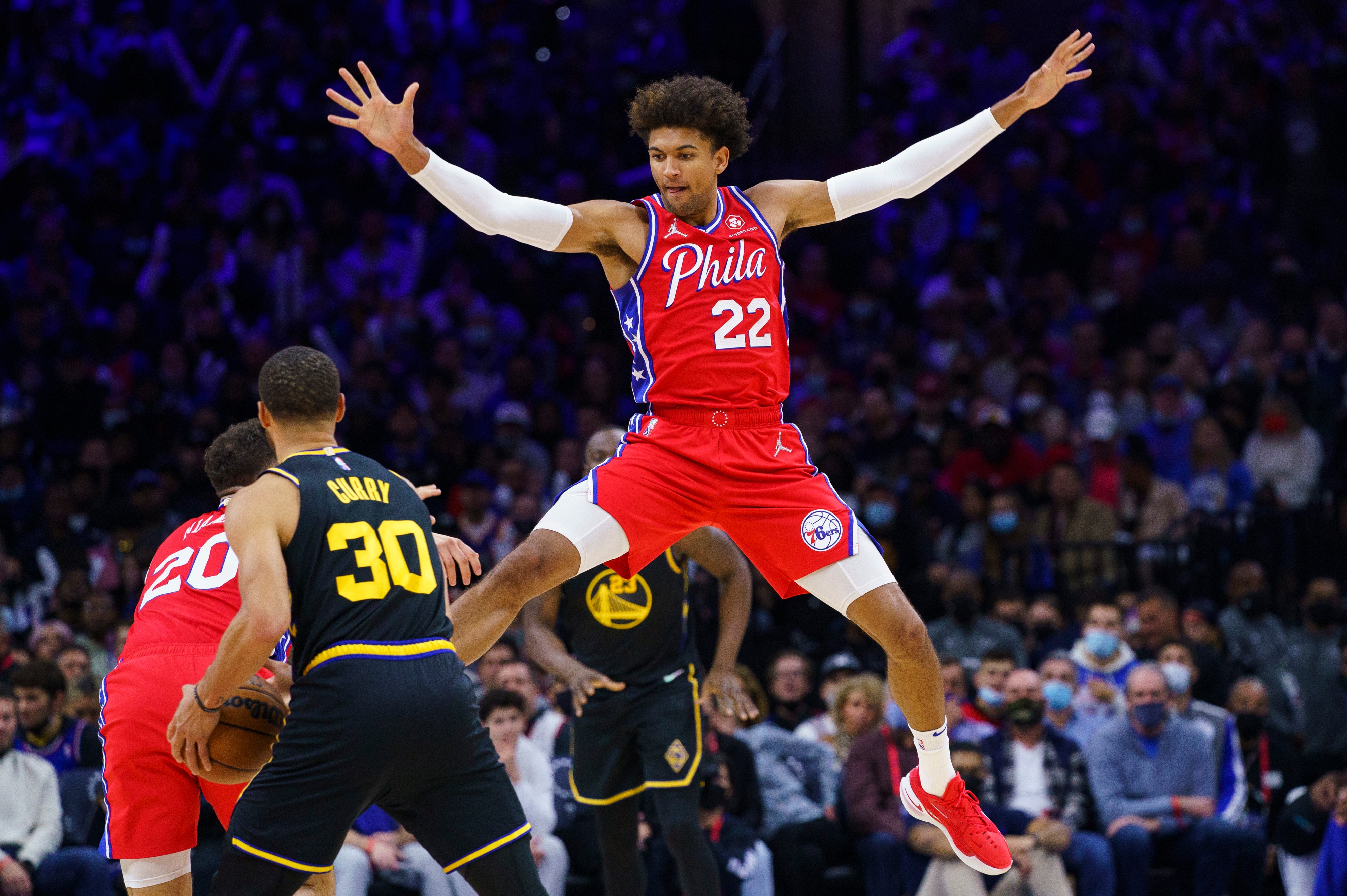 Philadelphia 76ers' Matisse Thybulle, right, leaps as he tries to defend against Golden State Warriors' Stephen Curry, front left, during the second half of an NBA basketball game, Saturday, Dec. 11, 2021, in Philadelphia. (AP Photo/Chris Szagola)