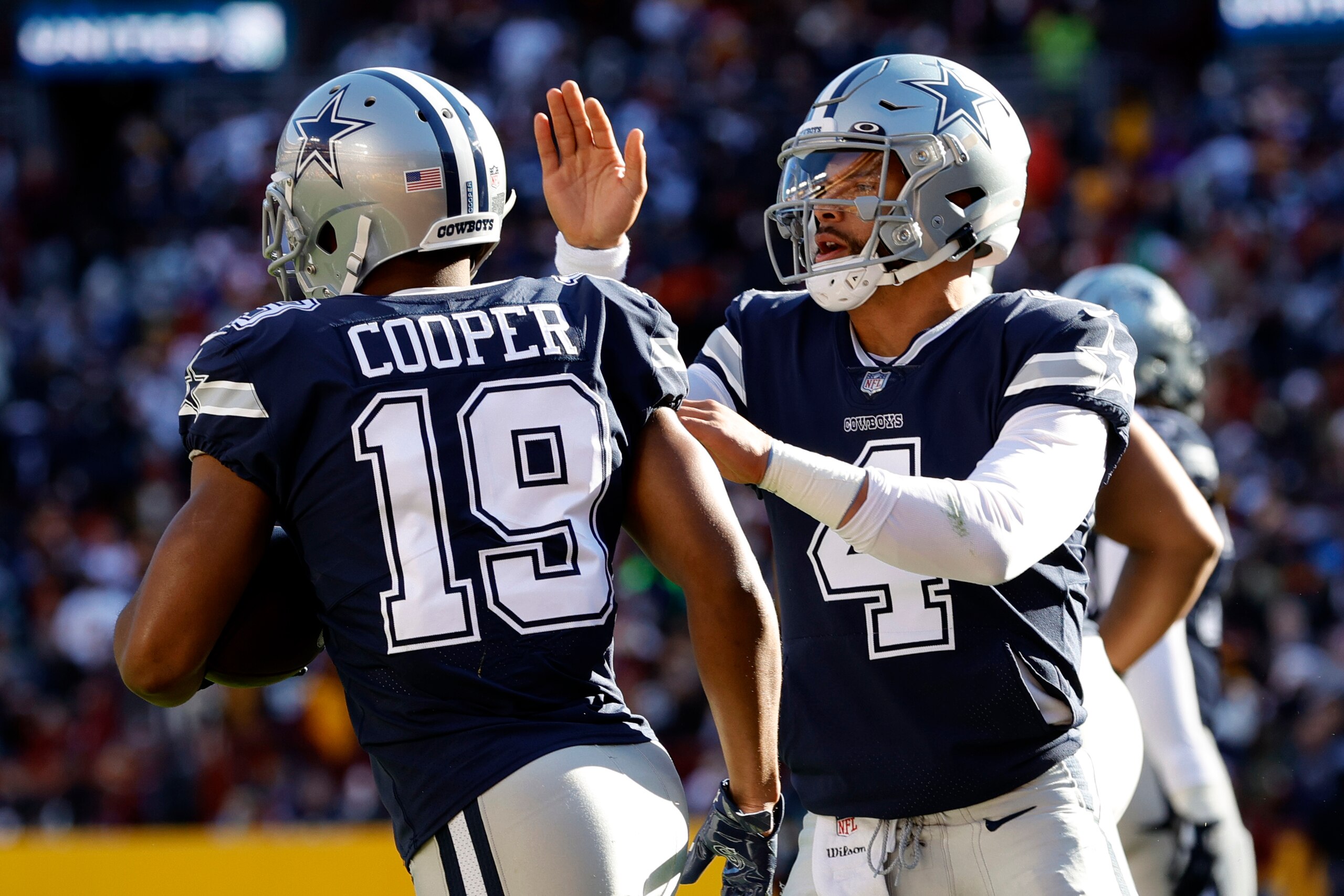 LANDOVER, MARYLAND - DECEMBER 12: Dak Prescott #4 of the Dallas Cowboys celebrates with Amari Cooper #19 after a seven-yard touchdown pass against the Washington Football Team during the first quarter at FedExField on December 12, 2021 in Landover, Maryland. (Photo by Rob Carr/Getty Images) LANDOVER, MARYLAND - DECEMBER 12: Dak Prescott #4 of the Dallas Cowboys celebrates with Amari Cooper #19 after a seven-yard touchdown pass against the Washington Football Team during the first quarter at FedExField on December 12, 2021 in Landover, Maryland. (Photo by Rob Carr/Getty Images)