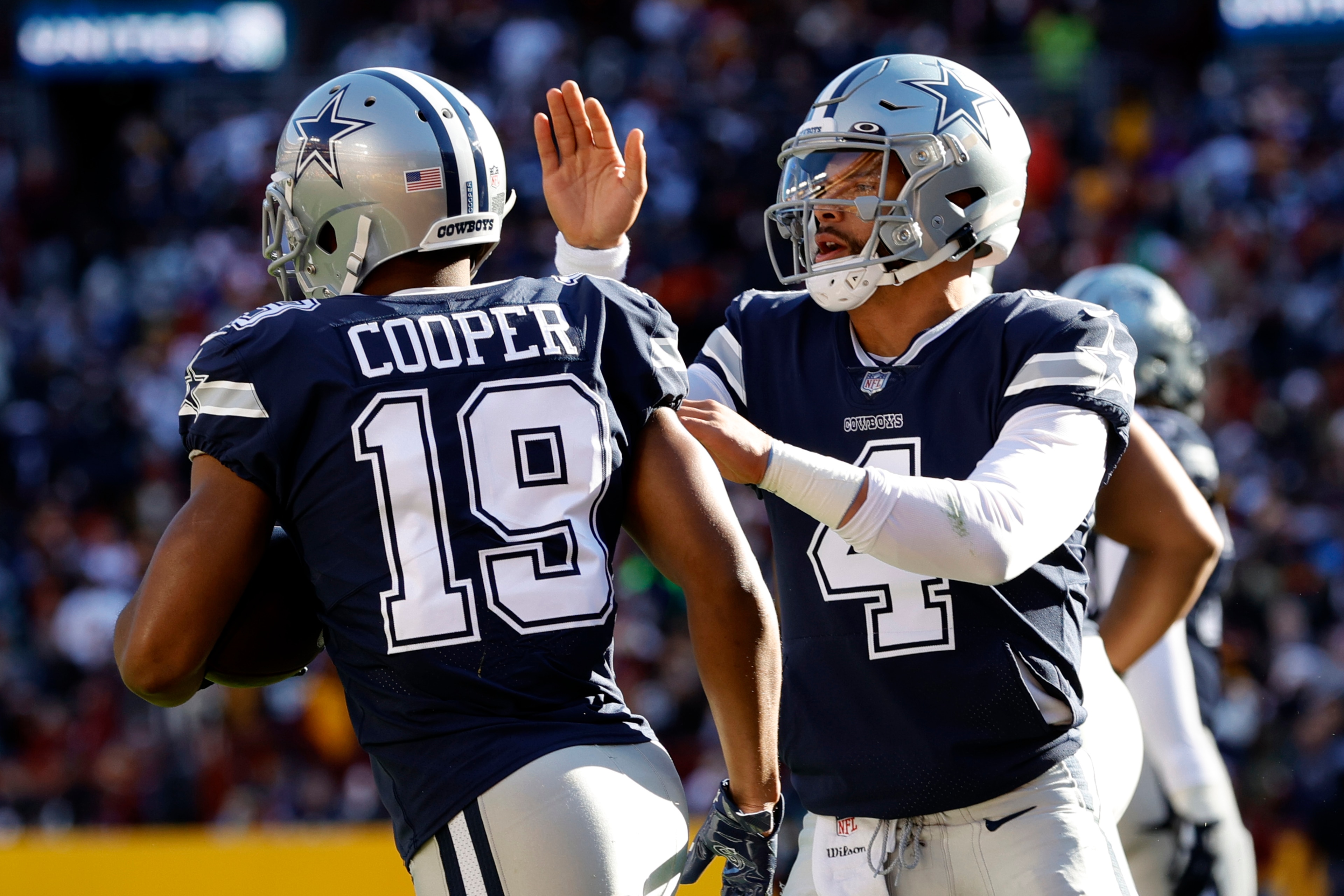 LANDOVER, MARYLAND - DECEMBER 12: Dak Prescott #4 of the Dallas Cowboys celebrates with Amari Cooper #19 after a seven-yard touchdown pass against the Washington Football Team during the first quarter at FedExField on December 12, 2021 in Landover, Maryland. (Photo by Rob Carr/Getty Images)