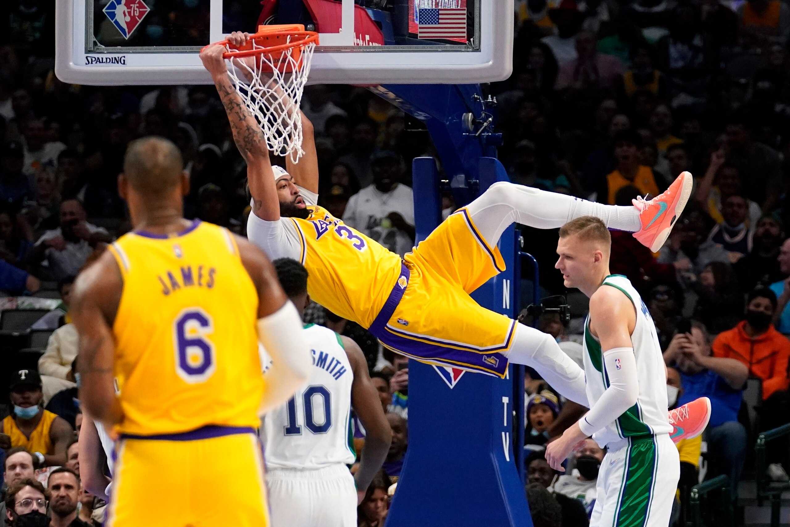 Los Angeles Lakers forward Anthony Davis (3) dunks over Dallas Mavericks' Dorian Finney-Smith (10) and Kristaps Porzingis, right, as LeBron James (6) looks on in the first half of an NBA basketball game in Dallas, Wednesday, Dec. 15, 2021. (AP Photo/Tony Gutierrez)