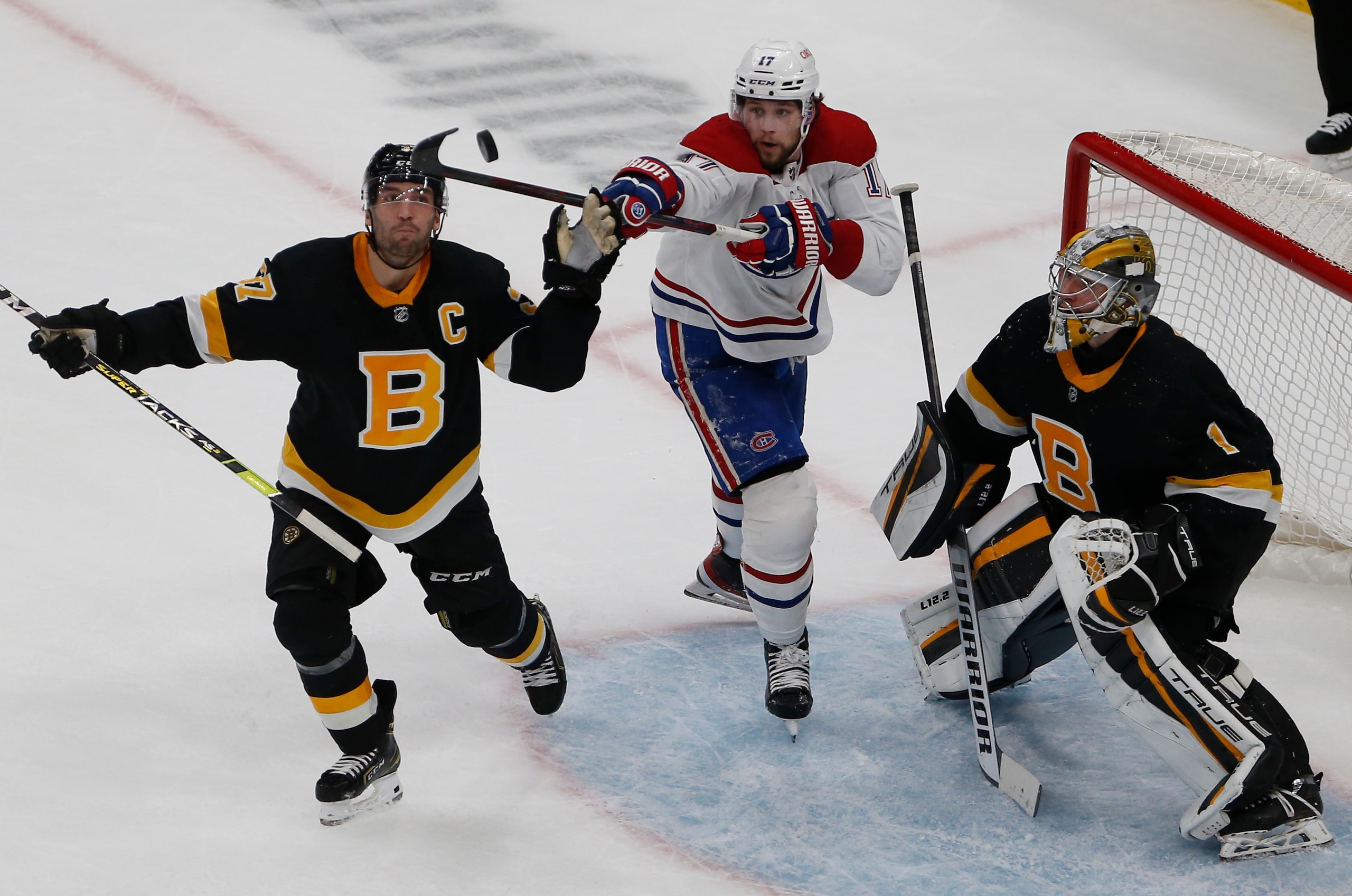 Boston - November 14: (L-R) Bruins Patrice Bergeron reaches up to catch the puck along with Canadiens Josh Anderson as Bruins goaltender Jeremy Swayman looks on during the second period. The Boston Bruins host the Montreal Canadiens in an NHL game at TD Garden in Boston on Nov. 14, 2021. (Photo by Jessica Rinaldi/The Boston Globe via Getty Images)