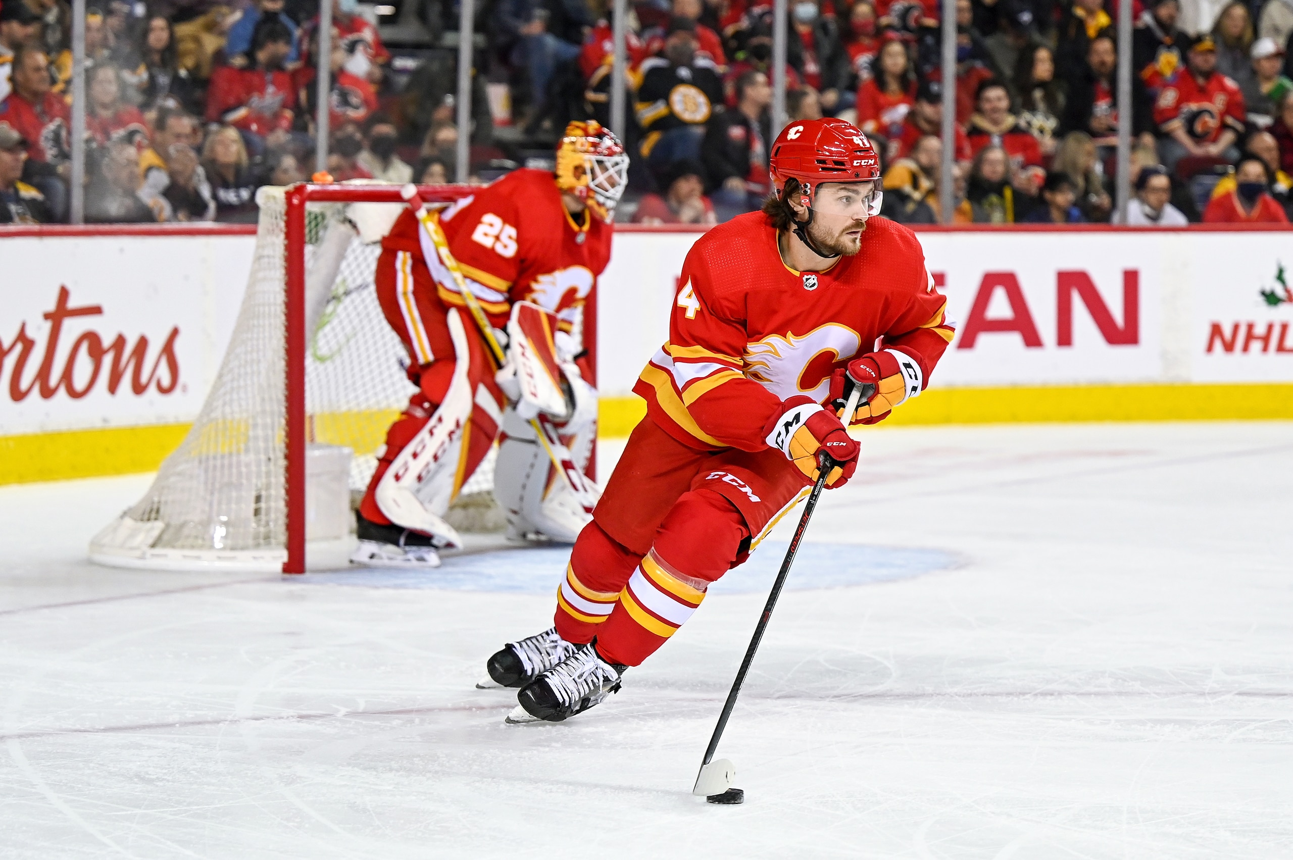 CALGARY, AB - DECEMBER 11: Calgary Flames Defenceman Rasmus Andersson (4) handles the puck in front of Calgary Flames Goalie Jacob Markstrom (25) during the first period of an NHL game where the Calgary Flames hosted the Boston Bruins on December 11, 2021, at the Scotiabank Saddledome in Calgary, AB. (Photo by Brett Holmes/Icon Sportswire via Getty Images) CALGARY, AB - DECEMBER 11: Calgary Flames Defenceman Rasmus Andersson (4) handles the puck in front of Calgary Flames Goalie Jacob Markstrom (25) during the first period of an NHL game where the Calgary Flames hosted the Boston Bruins on December 11, 2021, at the Scotiabank Saddledome in Calgary, AB. (Photo by Brett Holmes/Icon Sportswire via Getty Images)