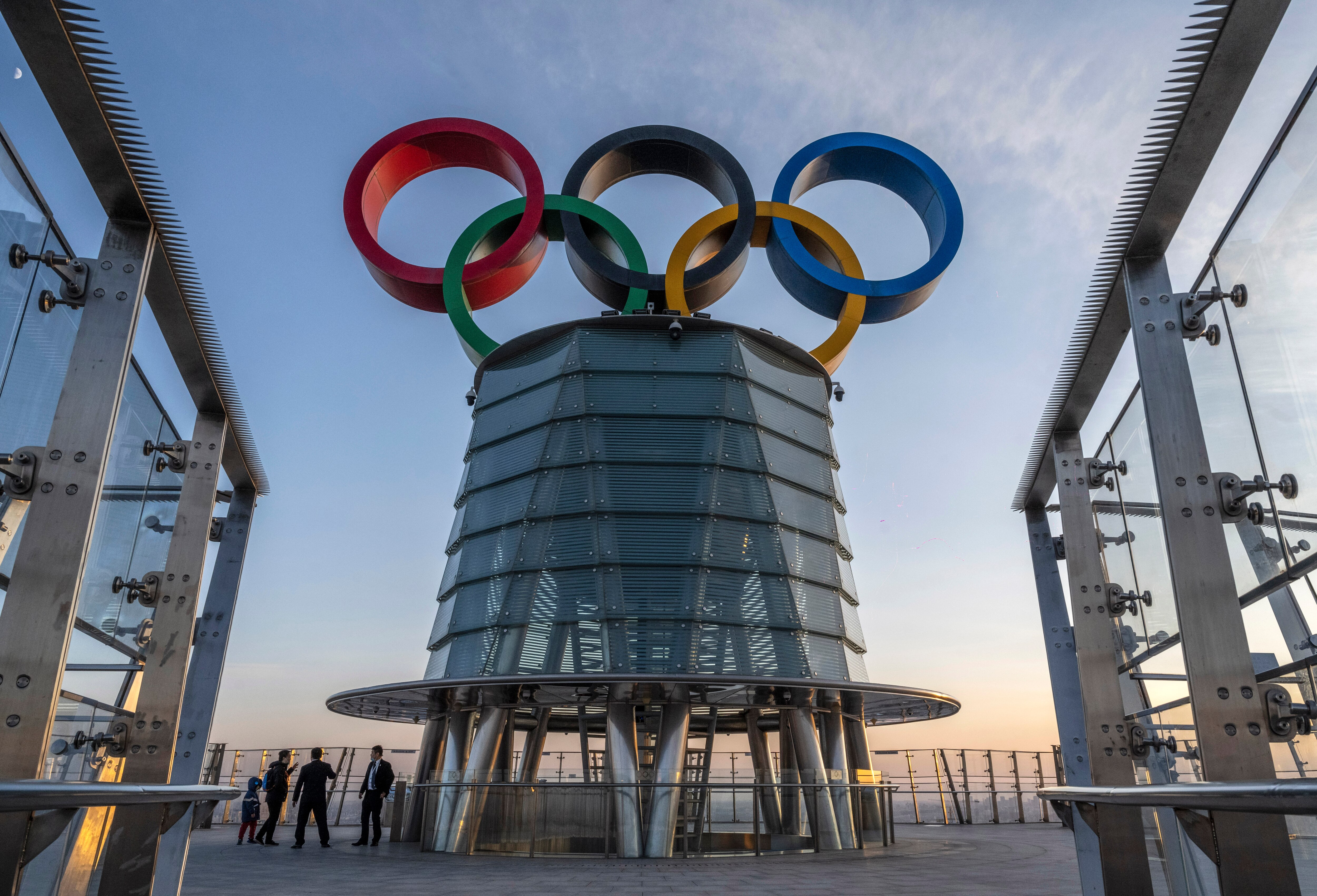 BEIJING, CHINA - DECEMBER 11: Visitors walk near a column with the Olympic Rings as they visit the top level of the Olympic Tower in the Olympic Green near the National Stadium, also known as the Bird's Nest, on December 11, 2021 in Beijing, China. The area will host a number of events for the Beijing 2022 Winter Olympic Games, including the opening ceremonies, which is set to open on February 4, 2022. (Photo by Kevin Frayer/Getty Images)