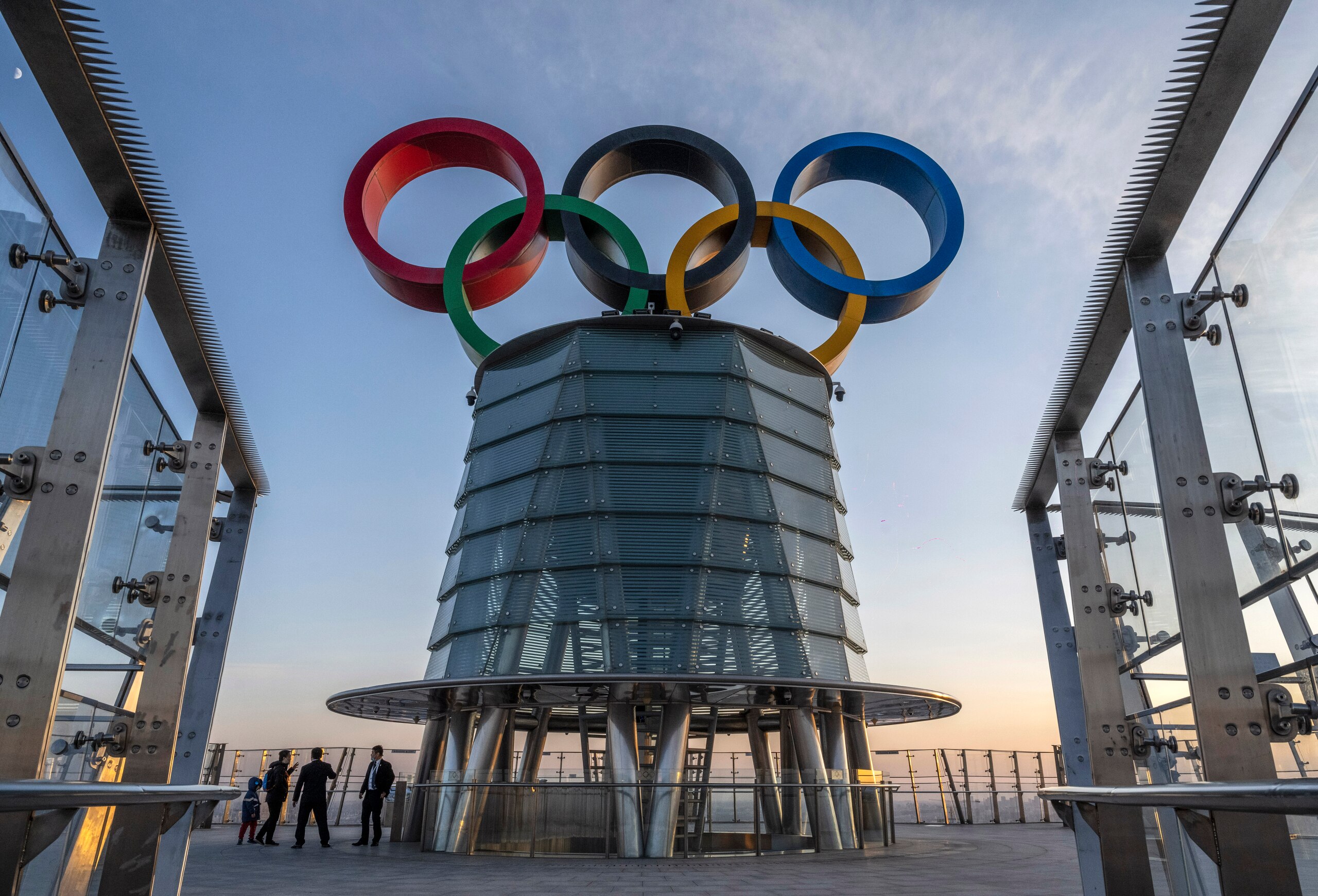 BEIJING, CHINA - DECEMBER 11: Visitors walk near a column with the Olympic Rings as they visit the top level of the Olympic Tower in the Olympic Green near the National Stadium, also known as the Bird's Nest, on December 11, 2021 in Beijing, China. The area will host a number of events for the Beijing 2022 Winter Olympic Games, including the opening ceremonies, which is set to open on February 4, 2022. (Photo by Kevin Frayer/Getty Images)