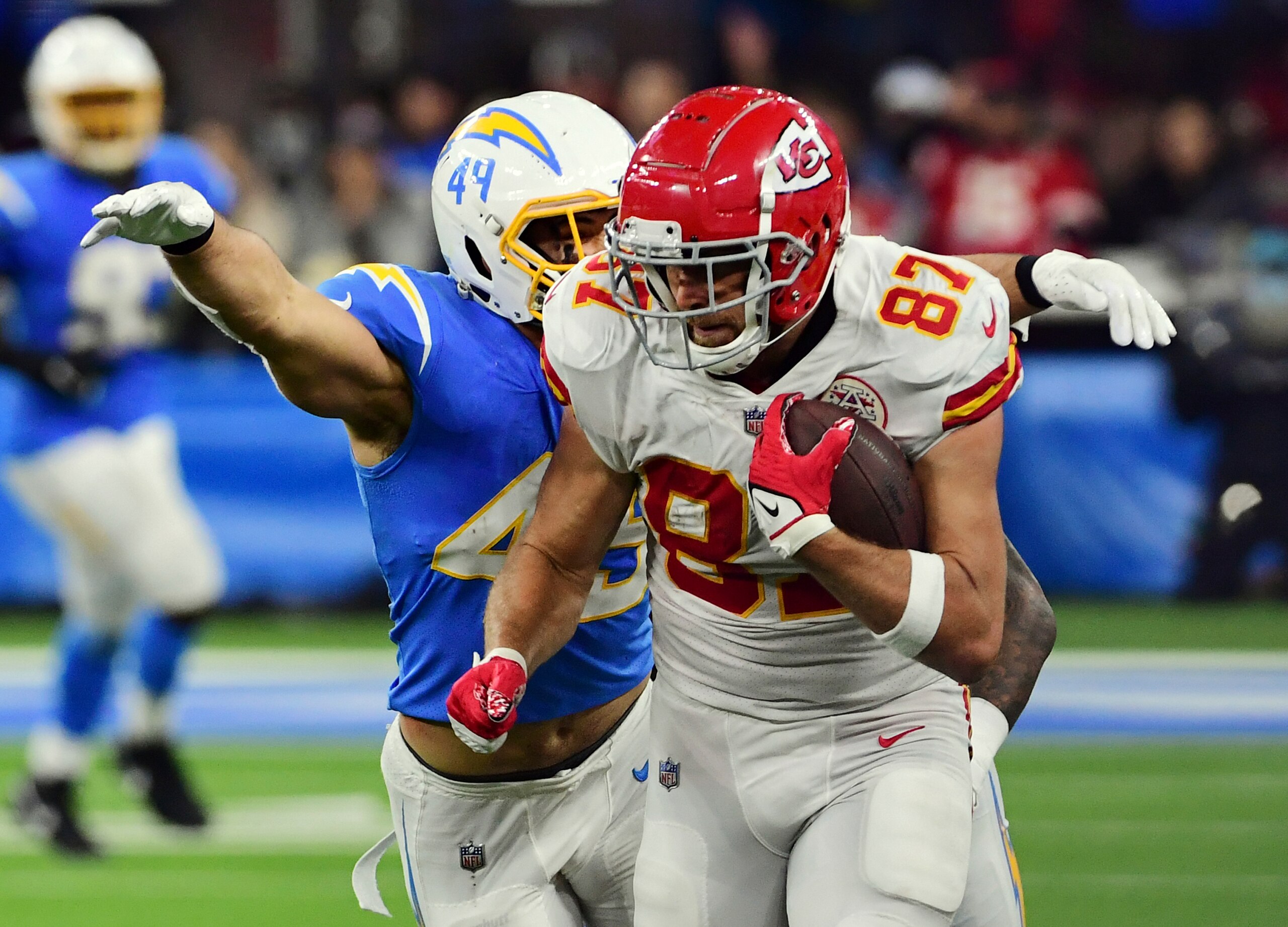 Kansas City Chiefs tight end Travis Kelce (87) tries to avoid being tackled by Los Angeles Chargers Drue Tranquill (49) after Kelce caught a pass for a first down during overtime of an NFL football game against the Chargers, Thursday, December 16, 2021 in Inglewood, Calif. The Chiefs defeated the Chargers 34 to 28. (John Cordes/AP Images for Panini)
