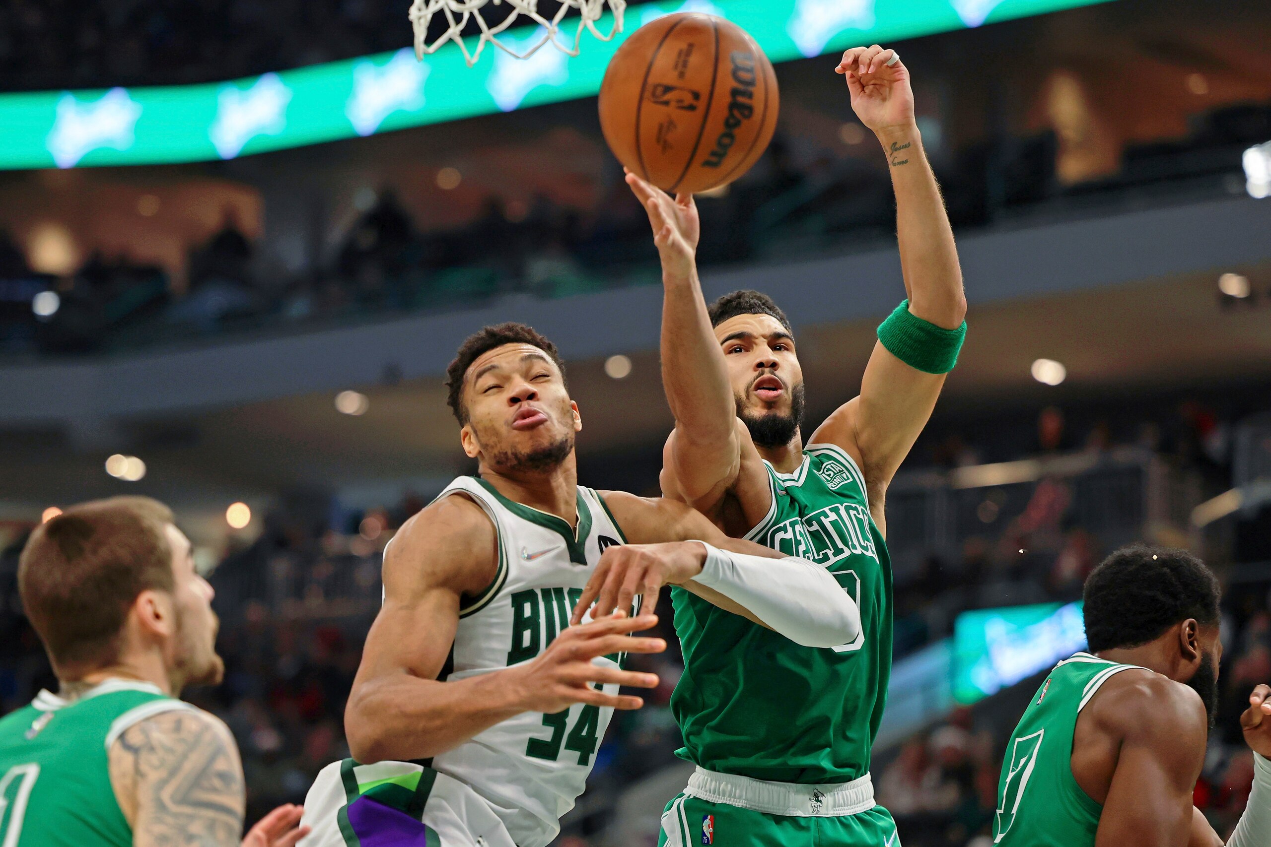 Boston Celtics forward Jayson Tatum, center, reaches for a rebound against Milwaukee Bucks forward Giannis Antetokounmpo (34) after chipping the tooth of guard Jaylen Brown, right, during the first half of an NBA basketball game Saturday, Dec. 25, 2021, in Milwaukee. (AP Photo/Jon Durr)