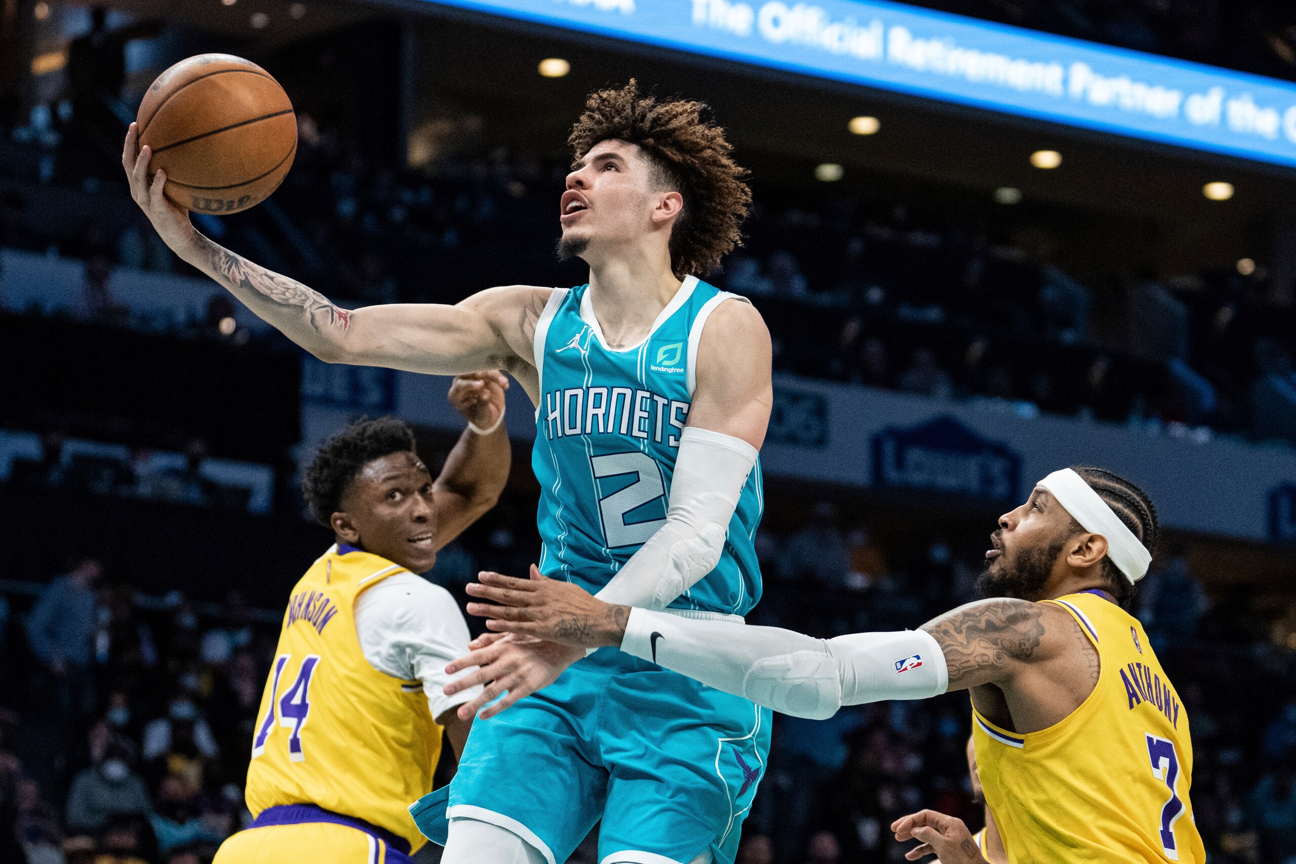 Charlotte Hornets guard LaMelo Ball (2) drives to the basket past Los Angeles Lakers forwards Stanley Johnson (14) and Carmelo Anthony (7) during the first half of an NBA basketball game in Charlotte, N.C., Friday, Jan. 28, 2022. (AP Photo/Jacob Kupferman)