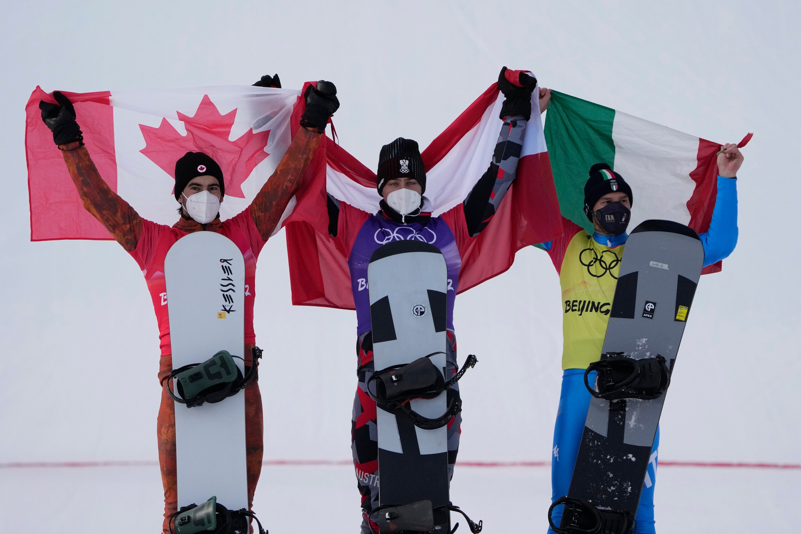 From left silver medal winner Canada's Éliot Grondin, gold medal winner Austria's Alessandro Haemmerle and bronze medal winner Italy's Omar Visintin celebrate during the venue award ceremony for during the men's cross finals at the 2022 Winter Olympics, Thursday, Feb. 10, 2022, in Zhangjiakou, China. (AP Photo/Lee Jin-man)