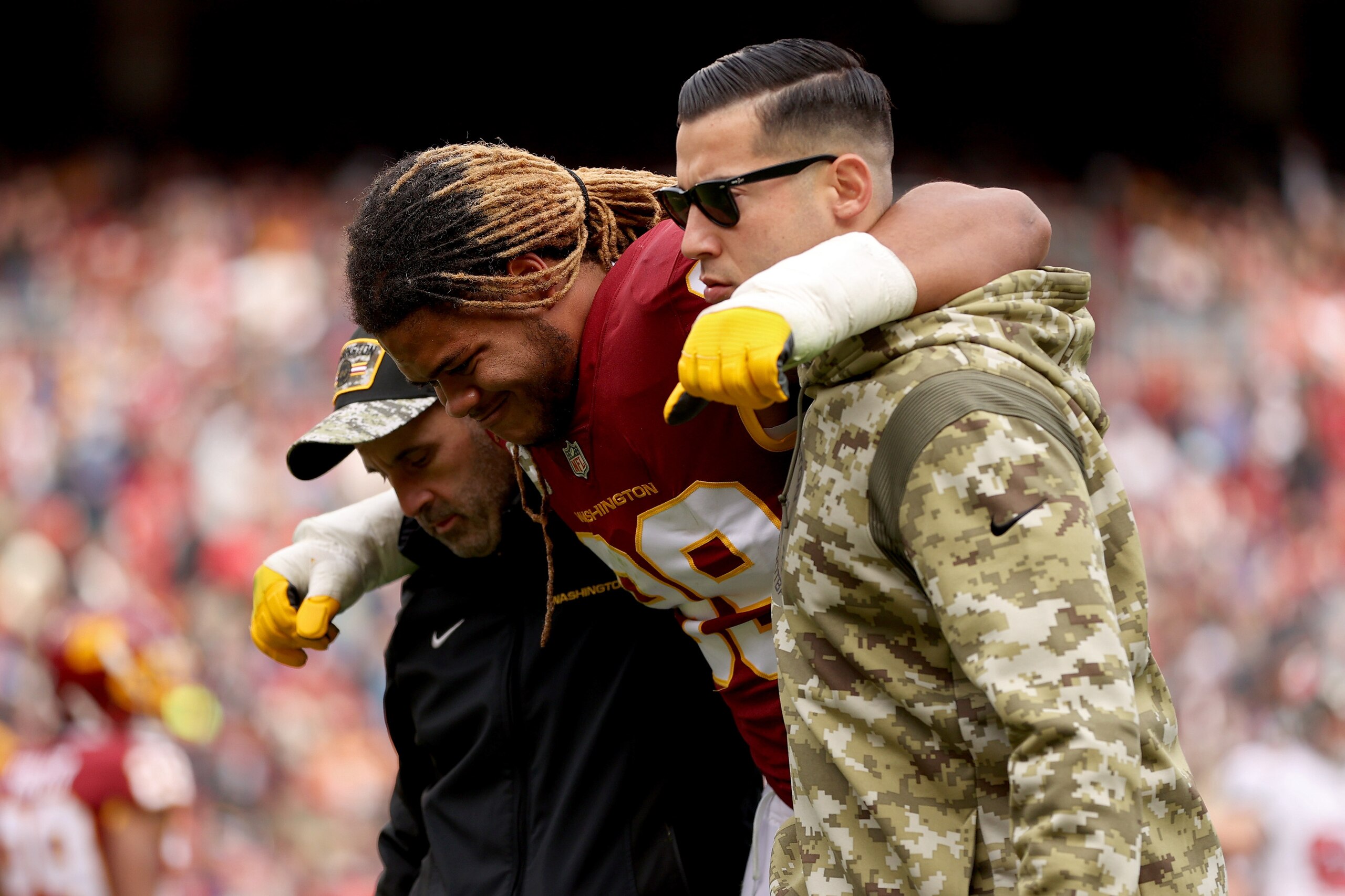 LANDOVER, MARYLAND - NOVEMBER 14: Chase Young #99 of the Washington Football Team is help off the field after an injury during the first half against the Tampa Bay Buccaneers at FedExField on November 14, 2021 in Landover, Maryland. (Photo by Patrick Smith/Getty Images)