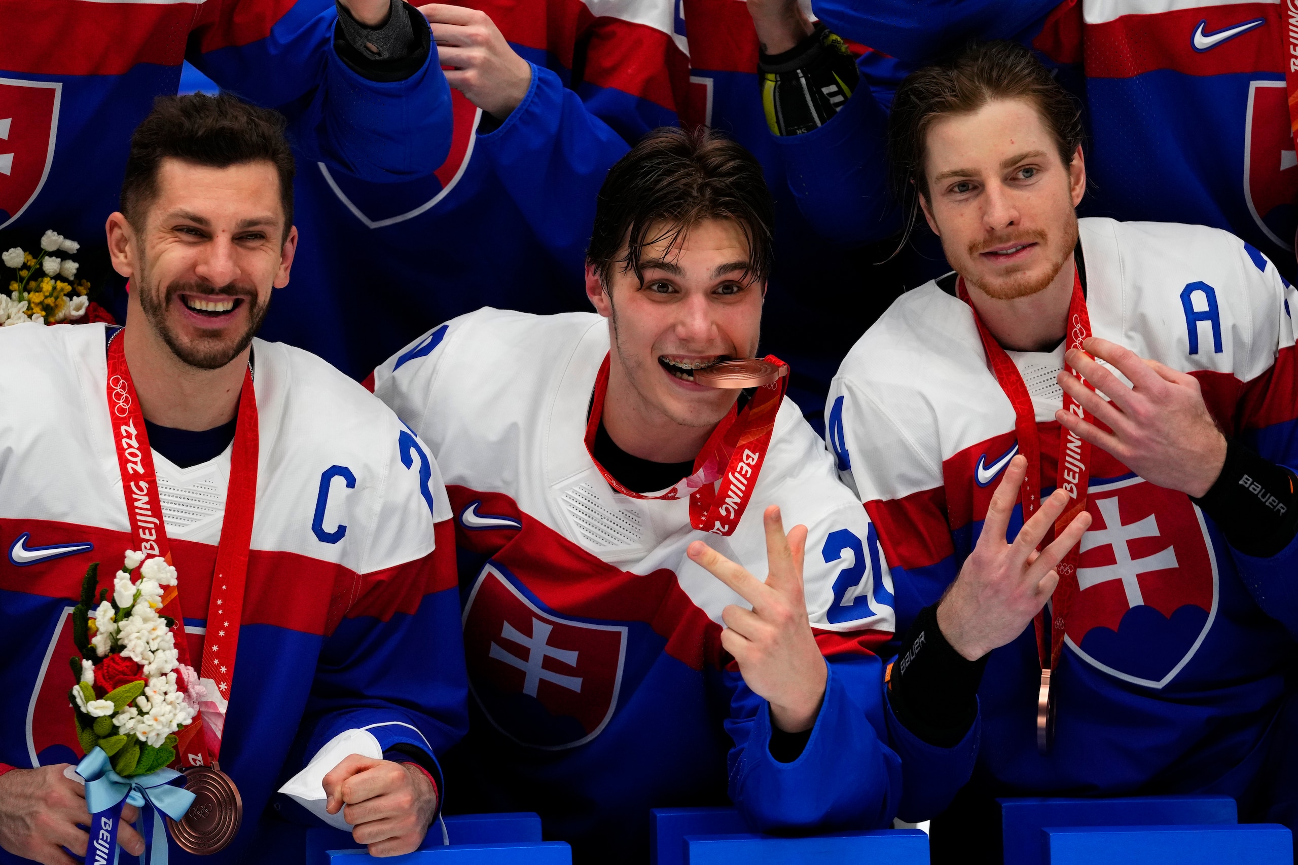 Slovakia's Marek Hrivik, from left, Slovakia's Juraj Slafkovsky, center, Slovakia's Peter Cehlarik pose with teammates after defeating Sweden in the men's bronze medal hockey game at the 2022 Winter Olympics, Saturday, Feb. 19, 2022, in Beijing. (AP Photo/Petr David Josek)