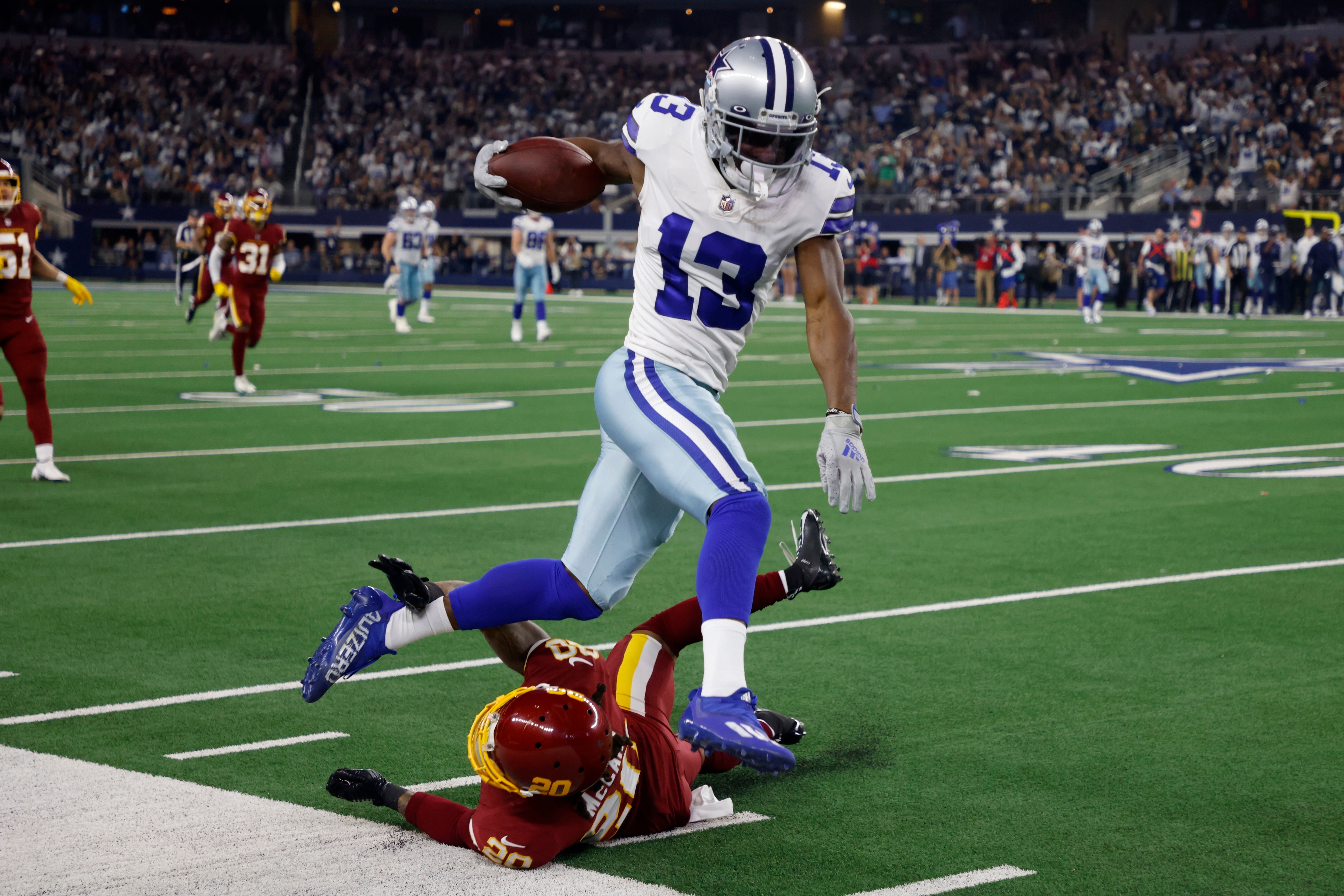 Dallas Cowboys wide receiver Michael Gallup (13) is stopped by Washington Football Team cornerback Bobby McCain (20) after catching a long pass in the first half of an NFL football game in Arlington, Texas, Sunday, Dec. 26, 2021. (AP Photo/Michael Ainsworth)