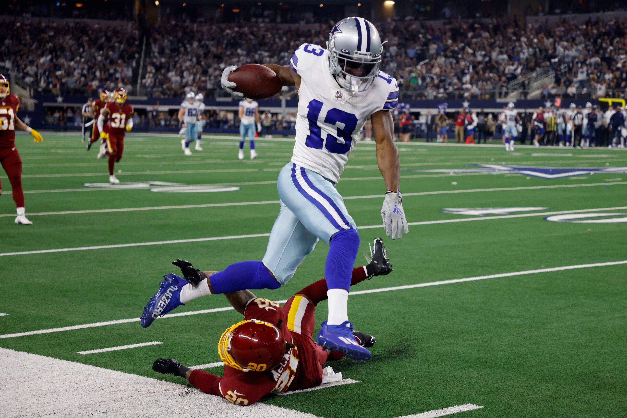 Dallas Cowboys wide receiver Michael Gallup (13) is stopped by Washington Football Team cornerback Bobby McCain (20) after catching a long pass in the first half of an NFL football game in Arlington, Texas, Sunday, Dec. 26, 2021. (AP Photo/Michael Ainsworth)