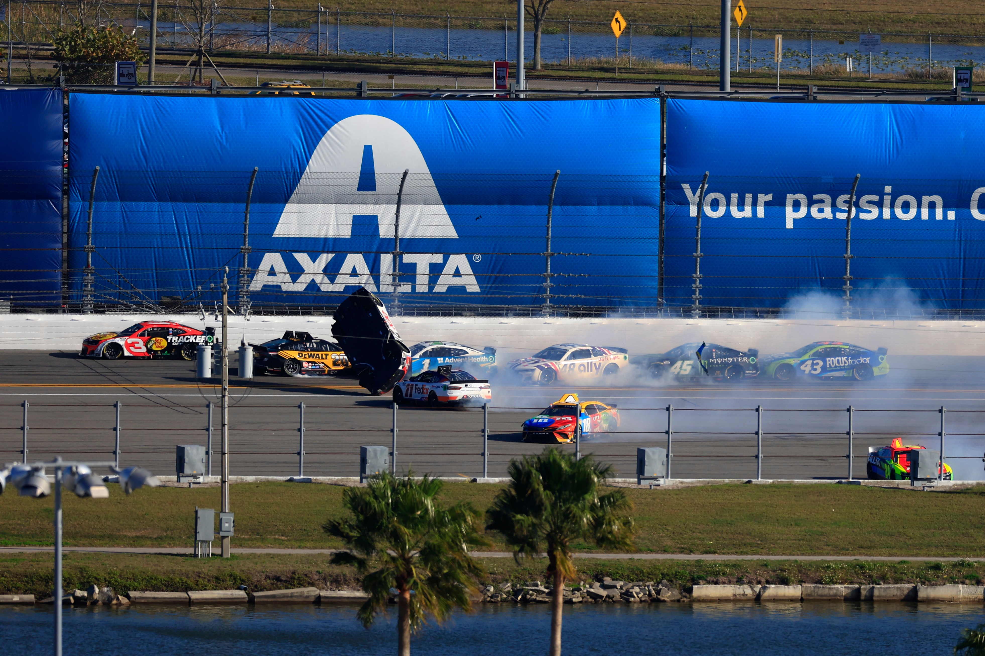 DAYTONA BEACH, FLORIDA - FEBRUARY 20: Harrison Burton, driver of the #21 Motorcraft/DEX Imaging Ford, flips after an on-track incident with Denny Hamlin, driver of the #11 FedEx Express Toyota, Ross Chastain, driver of the #1 Advent Health Chevrolet, and Kyle Busch, driver of the #18 M&M's Toyota, ,during the NASCAR Cup Series 64th Annual Daytona 500 at Daytona International Speedway on February 20, 2022 in Daytona Beach, Florida. (Photo by Mike Ehrmann/Getty Images)