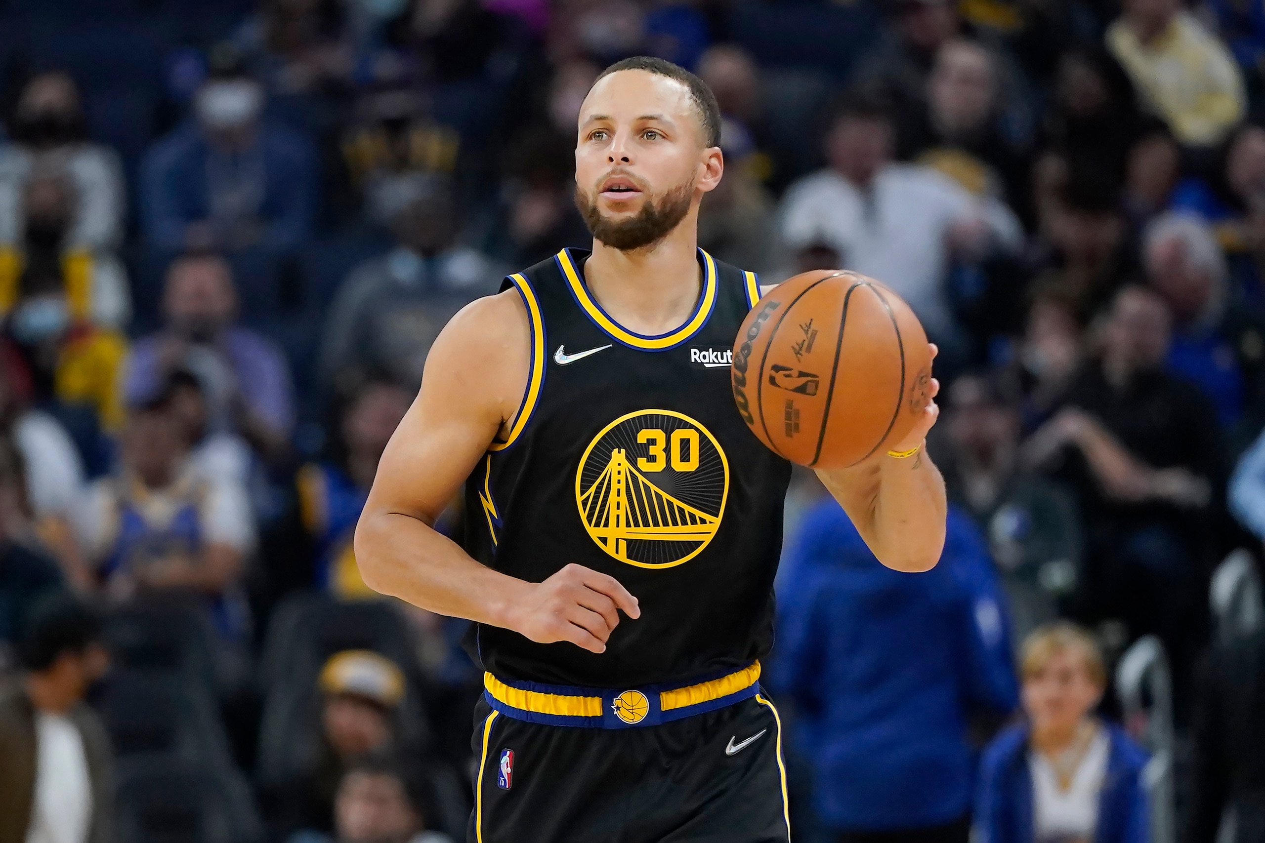 Golden State Warriors guard Stephen Curry dribbles the ball up the court against the Dallas Mavericks during the second half of an NBA basketball game in San Francisco, Sunday, Feb. 27, 2022. (AP Photo/Jeff Chiu)