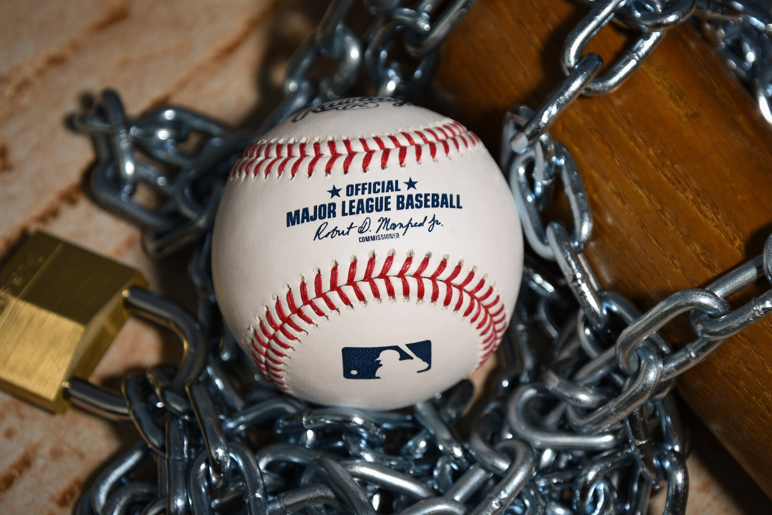 Brownsburg, IN - December 2: An Official Rawlings Major League Baseball sits with a bat, lock and chain to represent the lockout between Major League Baseball (MLB) and the Major League Baseball Players Association (MLBPA) on December 2, 2021 in Brownsburg, IN. (Photo by James Black/Icon Sportswire via Getty Images)