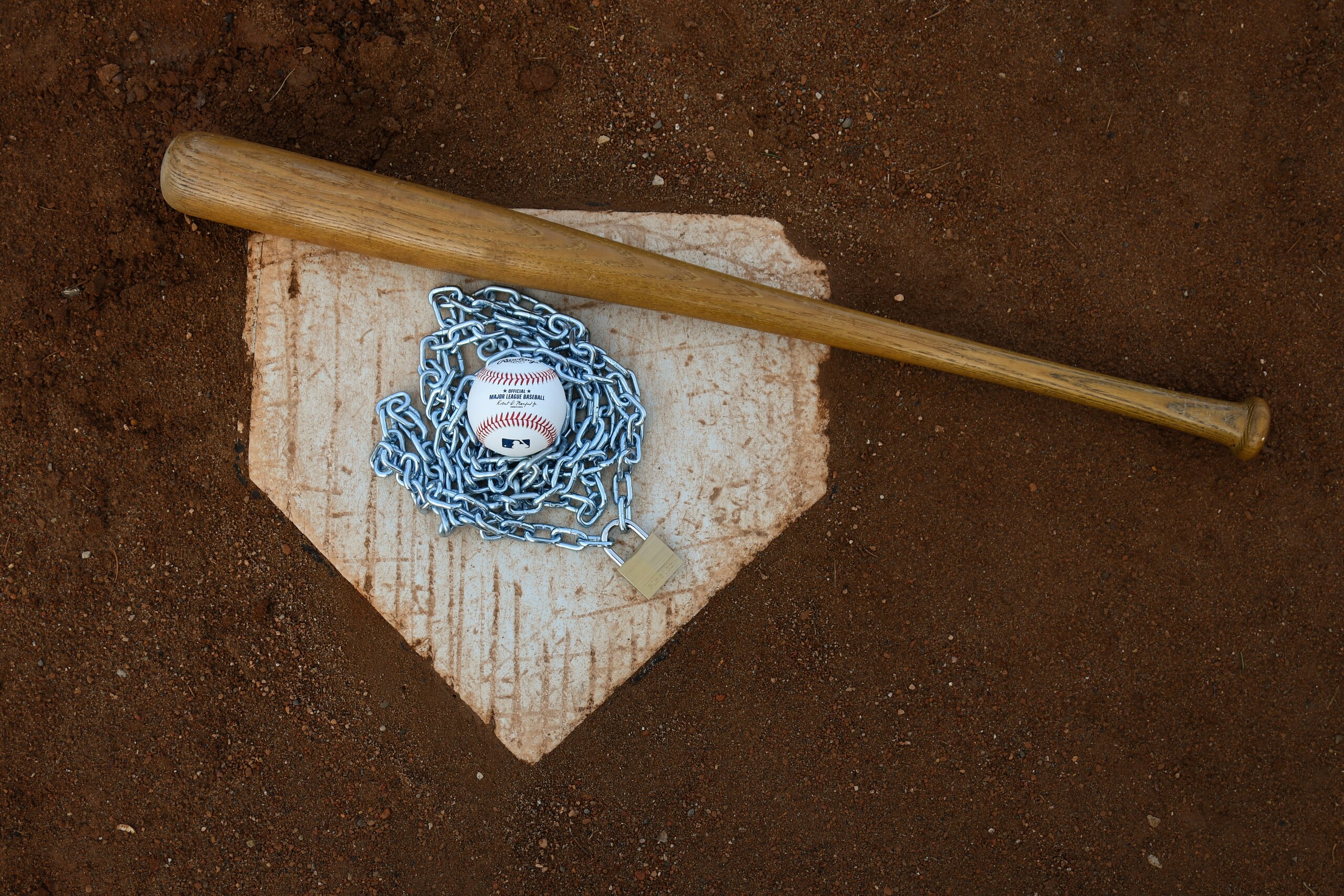Brownsburg, IN - December 2: An Official Rawlings Major League Baseball sits with a bat, lock and chain to represent the lockout between Major League Baseball (MLB) and the Major League Baseball Players Association (MLBPA) on December 2, 2021 in Brownsburg, IN. (Photo by James Black/Icon Sportswire via Getty Images) Brownsburg, IN - December 2: An Official Rawlings Major League Baseball sits with a bat, lock and chain to represent the lockout between Major League Baseball (MLB) and the Major League Baseball Players Association (MLBPA) on December 2, 2021 in Brownsburg, IN. (Photo by James Black/Icon Sportswire via Getty Images)