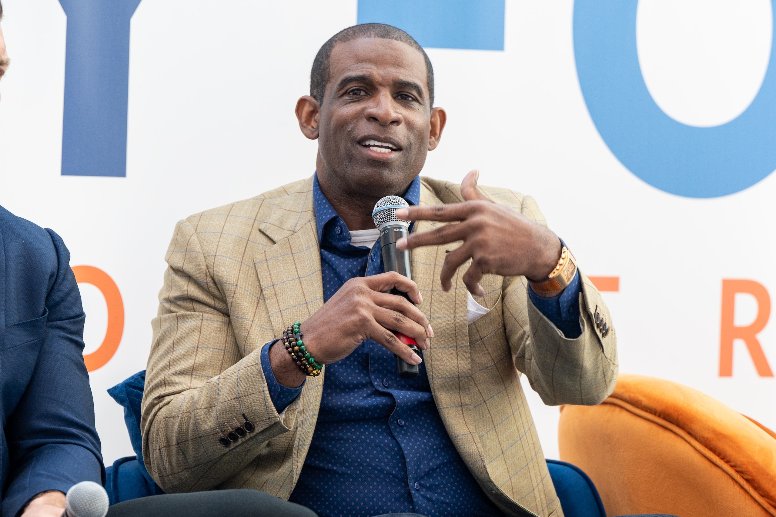 ATLANTA, GEORGIA - MARCH 04: Deion Sanders speaks on stage during the 2022 International Poverty Forum at Porsche Cars North America on March 04, 2022 in Atlanta, Georgia. (Photo by Derek White/Getty Images)