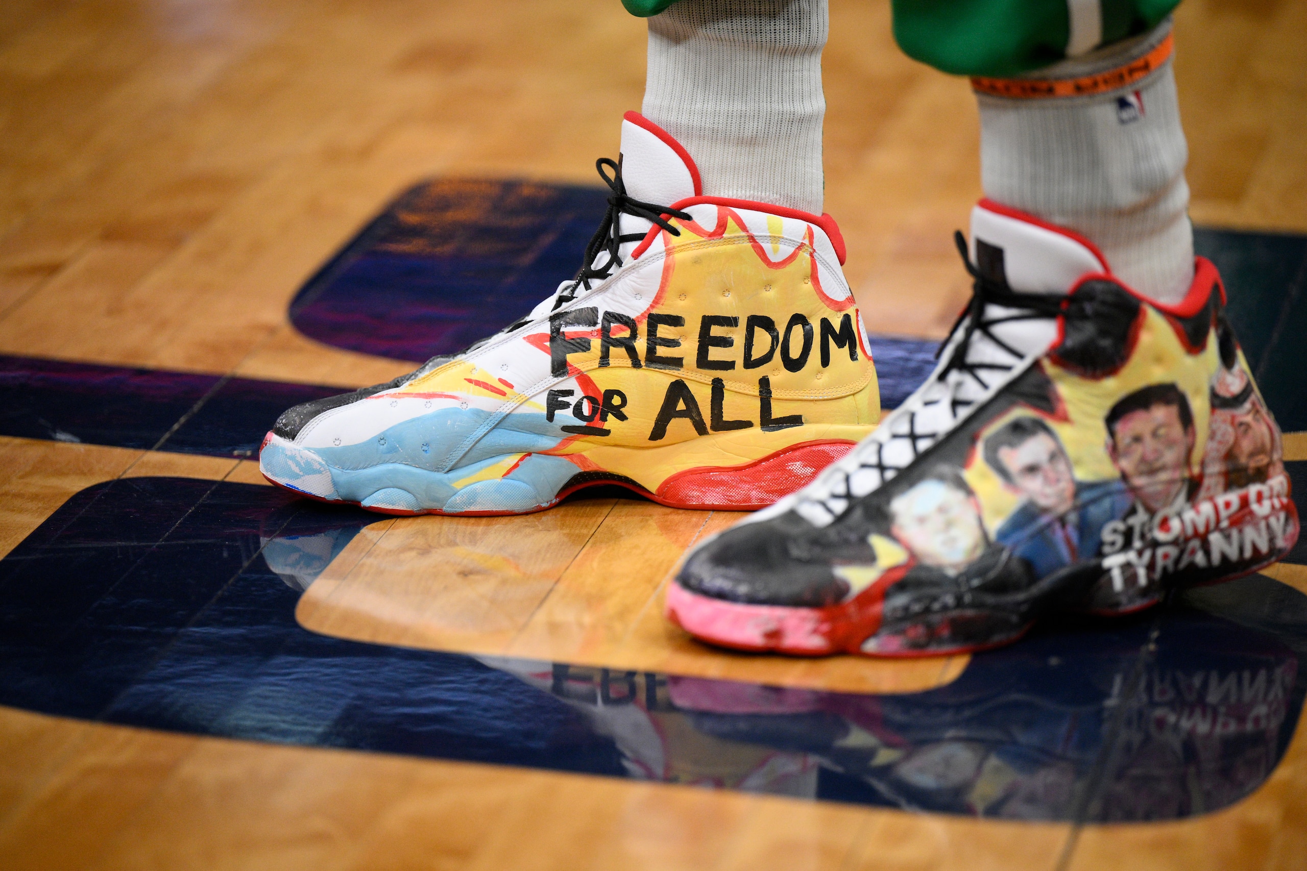 Shoes worn by Boston Celtics center Enes Freedom are seen as he stands on the court before an NBA basketball game against the Washington Wizards, Sunday, Jan. 23, 2022, in Washington. (AP Photo/Nick Wass)