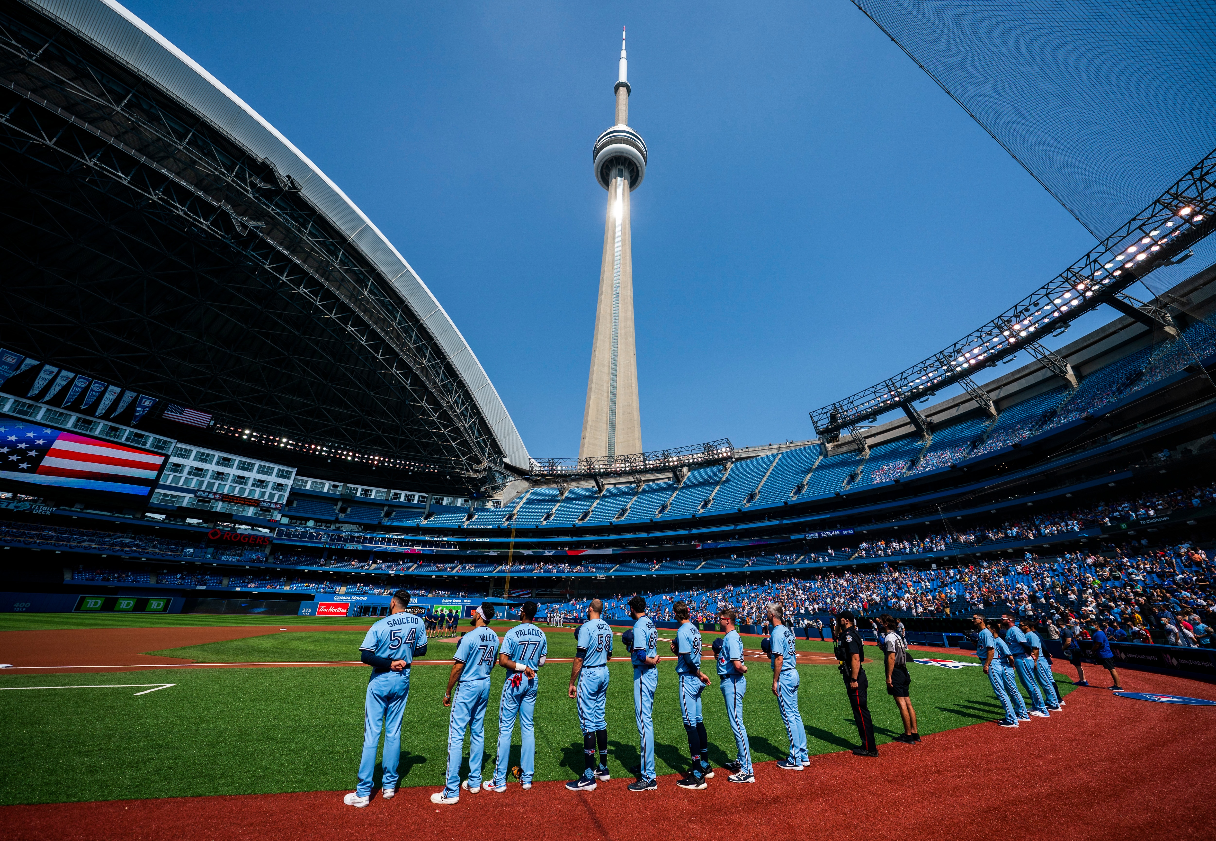 TORONTO, ONTARIO - AUGUST 26: Toronto Blue Jays players stand for the national anthem under the CN Tower before playing the Chicago White Sox in their MLB game at the Rogers Centre on August 26, 2021 in Toronto, Ontario, Canada. (Photo by Mark Blinch/Getty Images)