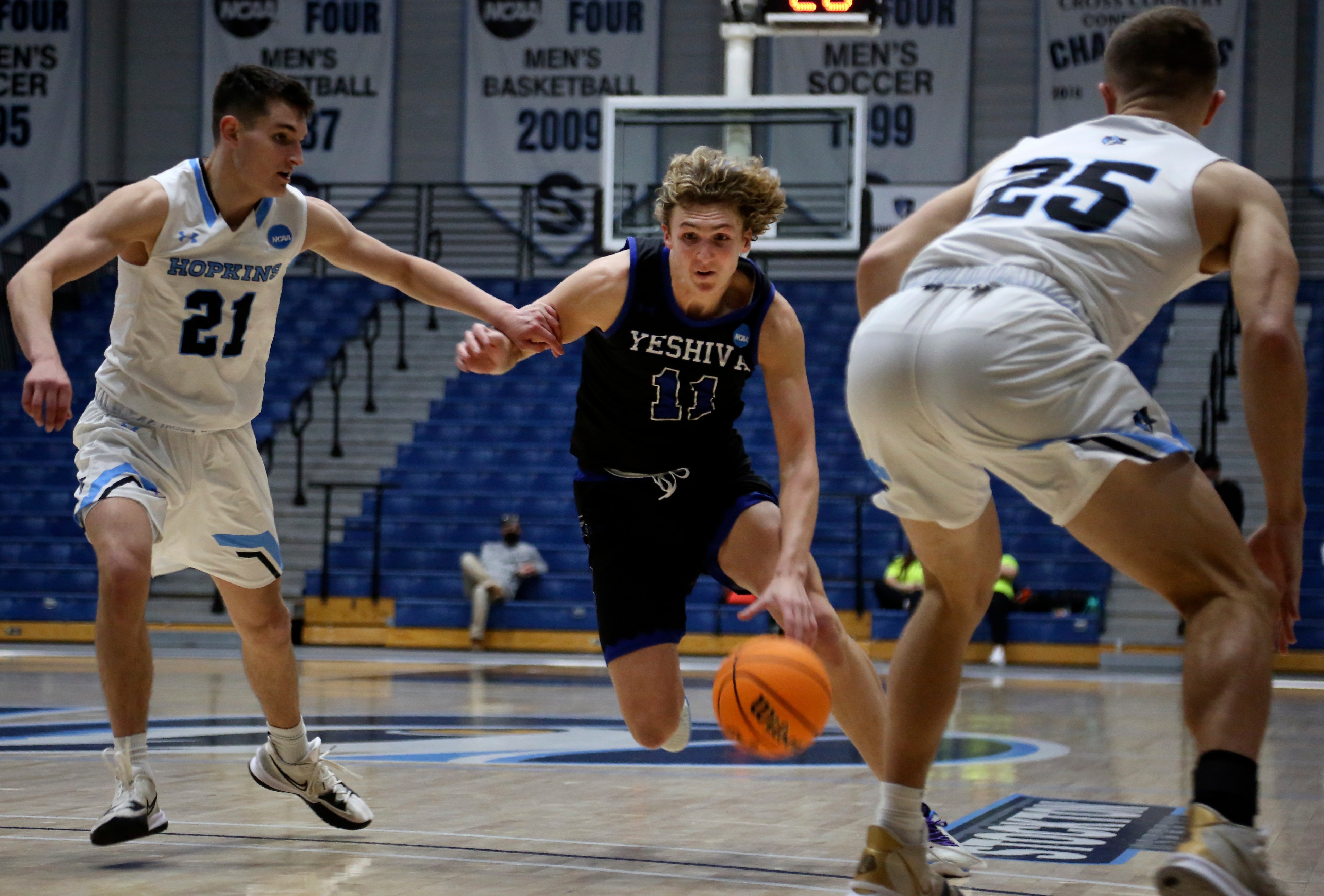 Yeshiva University's Ryan Turell (11) dribbles the ball down court while being defended by Johns Hopkins University's Carson James (21) and Lincoln Yeutter (25) in the first round of the NCAA's Division III basketball tournament, in Galloway Township, N.J., on Friday, March 4, 2022. The Yeshiva Maccabees lost to the Blue Jays, 63-59 at Stockton University Sports Center. (AP Photo/Jessie Wardarski)