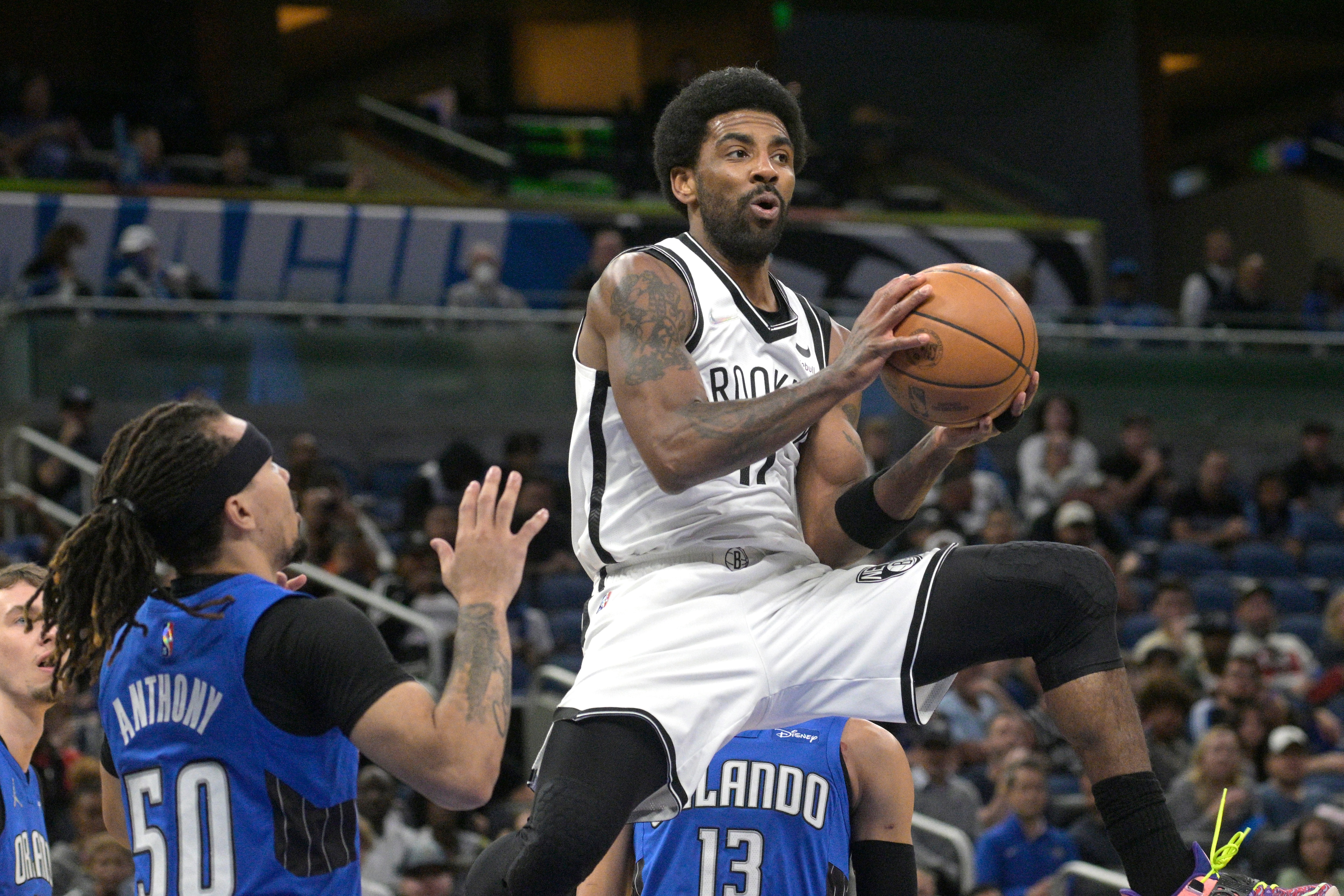 Brooklyn Nets guard Kyrie Irving (11) looks to pass after driving to the basket as Orlando Magic guard Cole Anthony (50) defends during the first half of an NBA basketball game Tuesday, March 15, 2022, in Orlando, Fla. (AP Photo/Phelan M. Ebenhack)