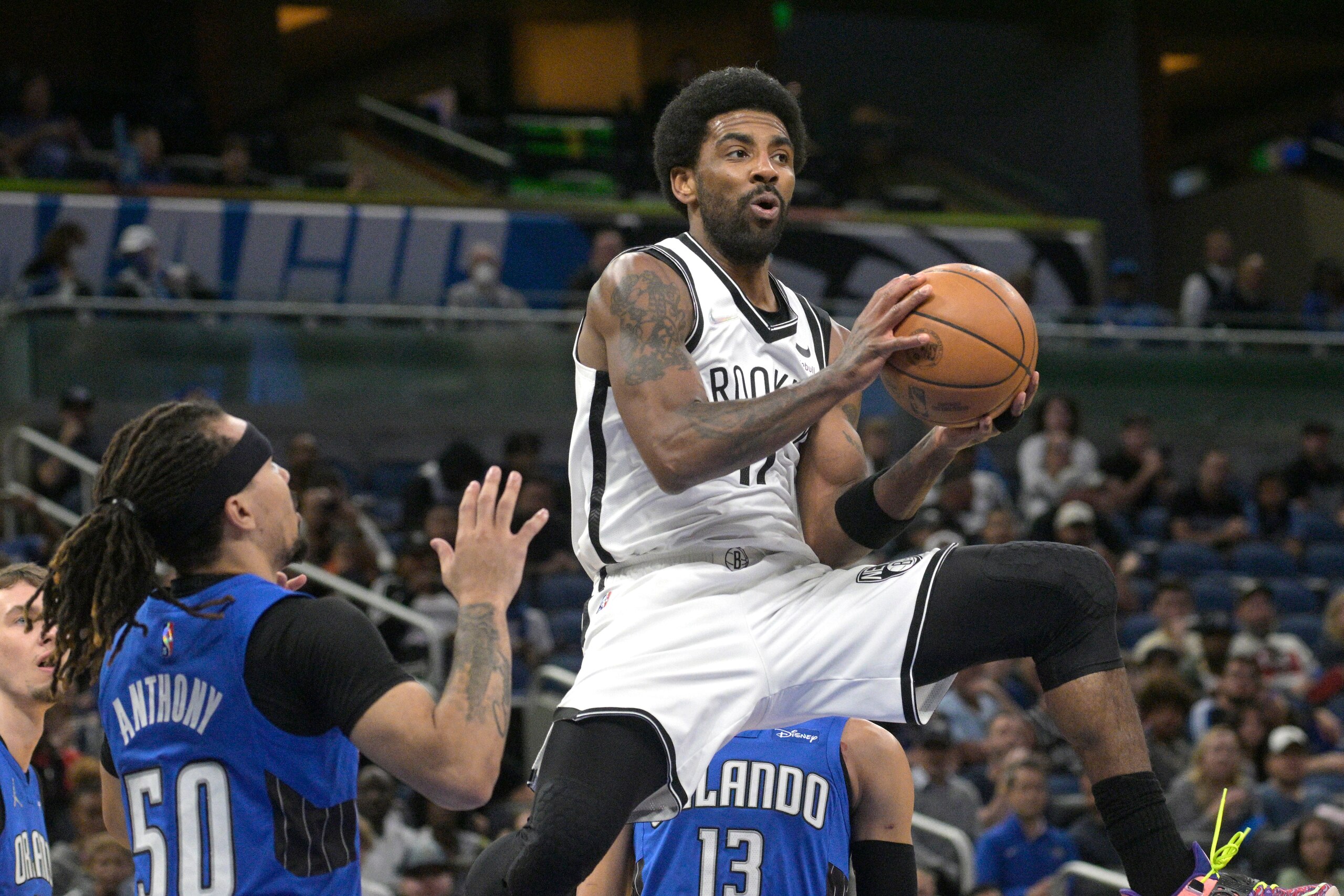 Brooklyn Nets guard Kyrie Irving (11) looks to pass after driving to the basket as Orlando Magic guard Cole Anthony (50) defends during the first half of an NBA basketball game Tuesday, March 15, 2022, in Orlando, Fla. (AP Photo/Phelan M. Ebenhack)