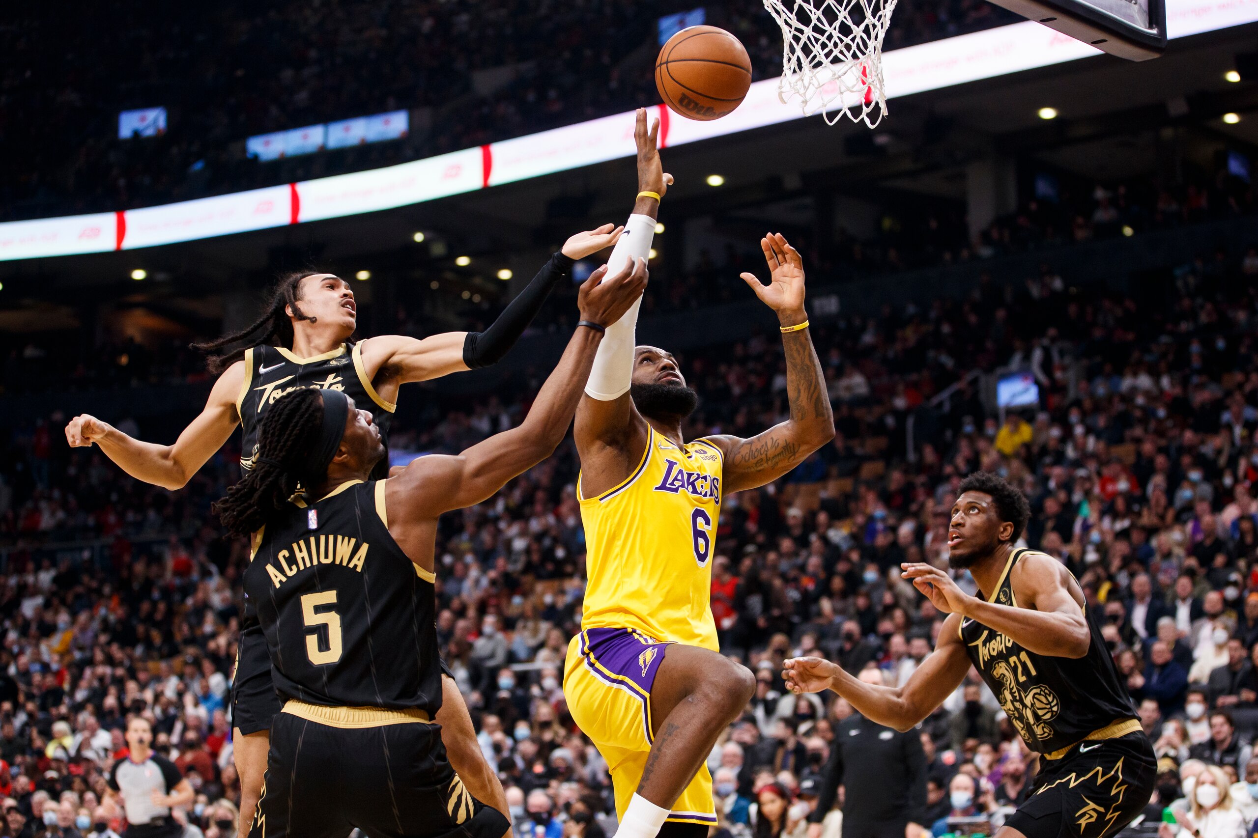 TORONTO, ON - MARCH 18: LeBron James #6 of the Los Angeles Lakers grabs a rebound against Dalano Banton #45, Precious Achiuwa #5 and Thaddeus Young #21 of the Toronto Raptors during the first half of their NBA game at Scotiabank Arena on March 18, 2022 in Toronto, Canada. NOTE TO USER: User expressly acknowledges and agrees that, by downloading and or using this Photograph, user is consenting to the terms and conditions of the Getty Images License Agreement. (Photo by Cole Burston/Getty Images)