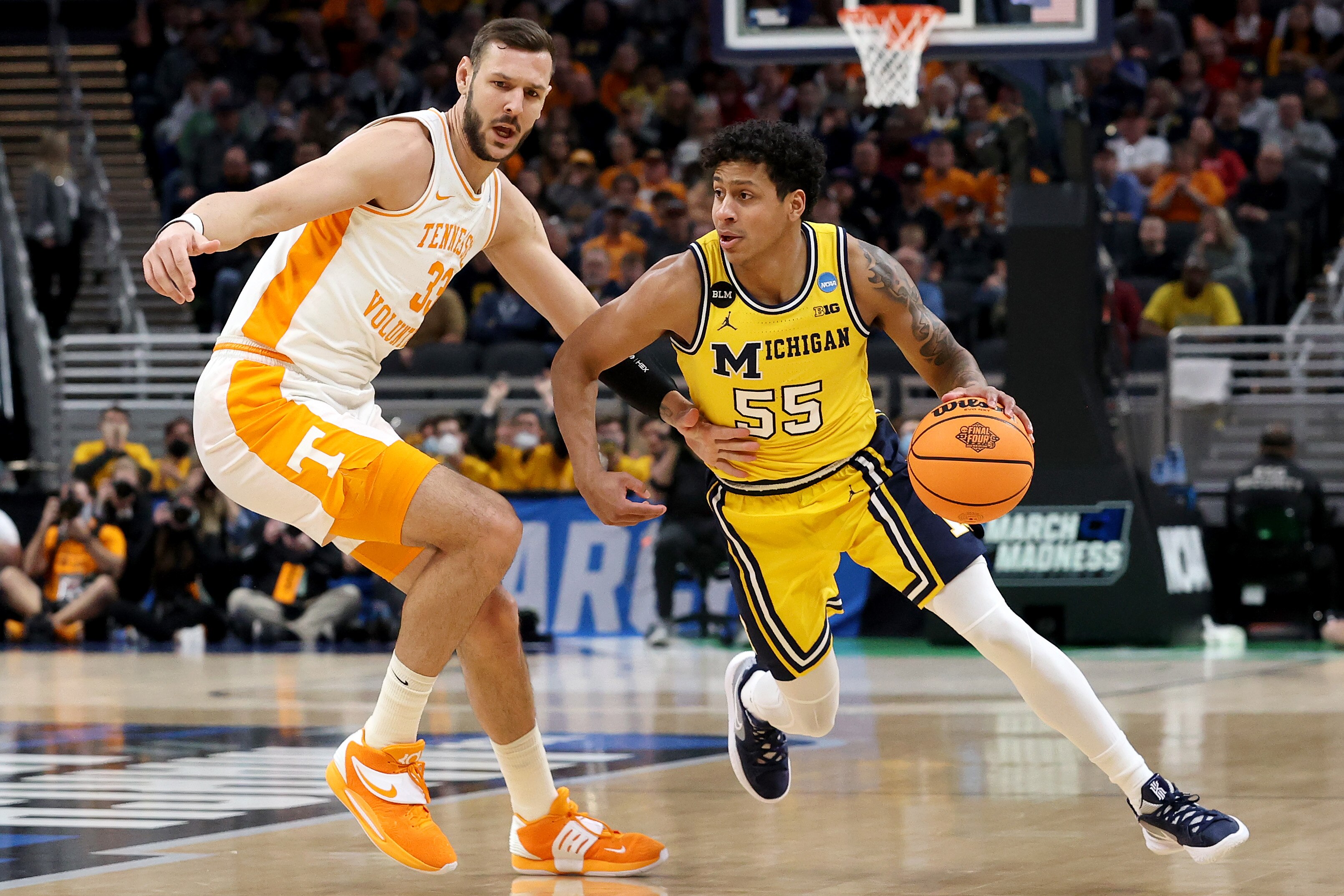 INDIANAPOLIS, INDIANA - MARCH 19: Eli Brooks #55 of the Michigan Wolverines drives past Uros Plavsic #33 of the Tennessee Volunteers in the first half during the second round of the 2022 NCAA Men's Basketball Tournament at Gainbridge Fieldhouse on March 19, 2022 in Indianapolis, Indiana. (Photo by Dylan Buell/Getty Images)