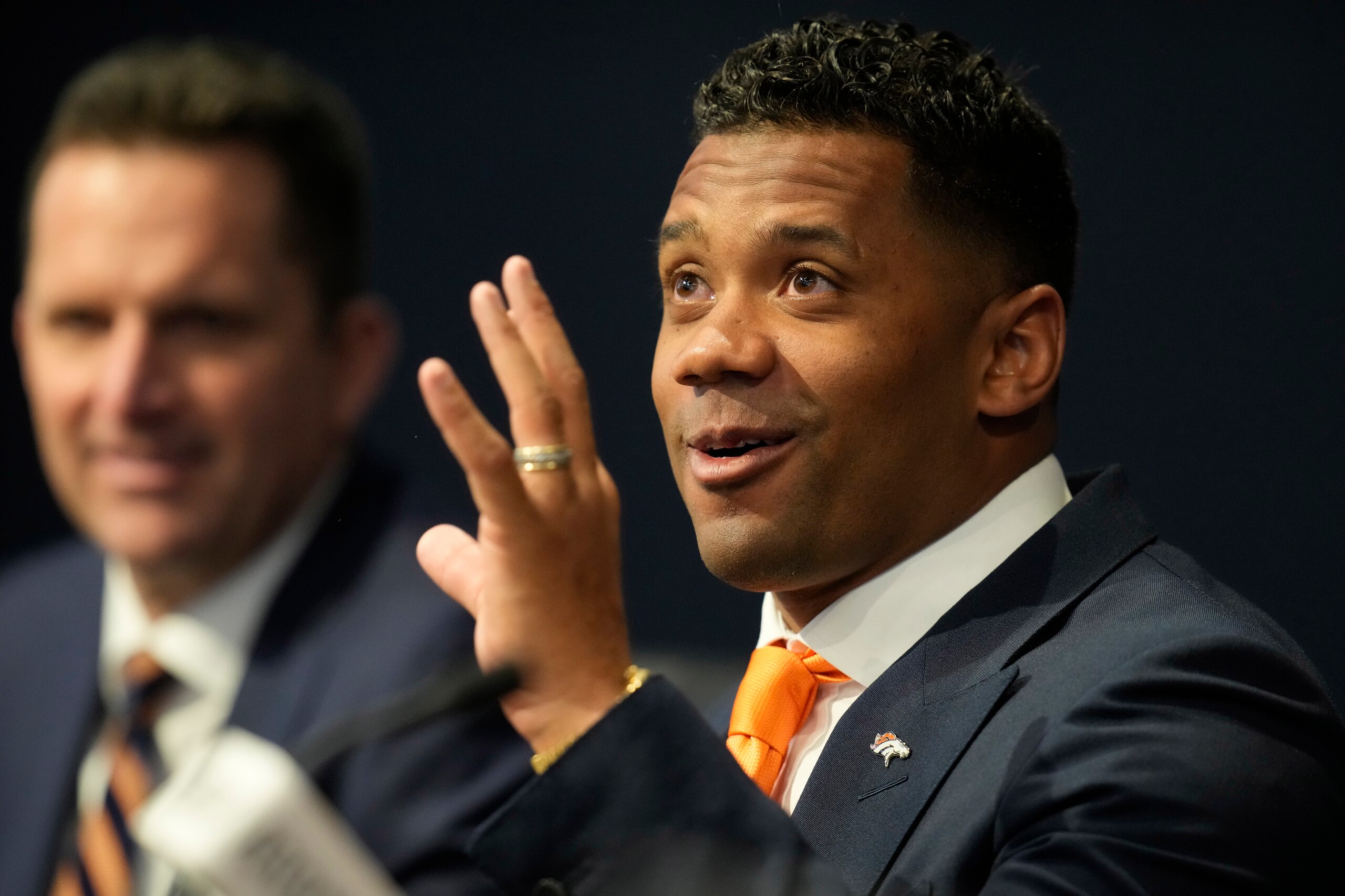 Denver Broncos new starting quarterback Russell Wilson makes a point as general manager George Paton looks on during a news conference Wednesday, March 16, 2022, at the team's headquarters in Englewood, Colo. (AP Photo/David Zalubowski)