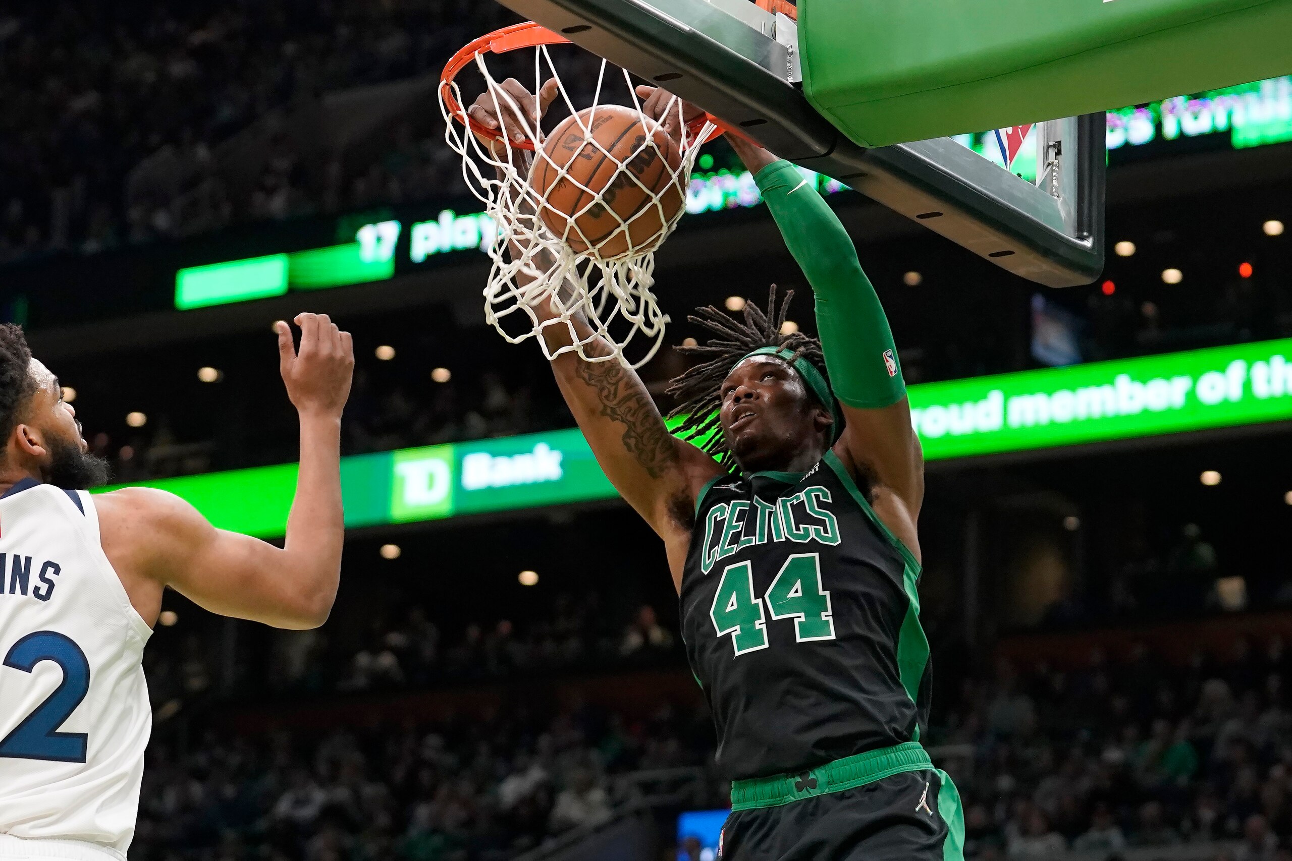 Boston Celtics center Robert Williams III (44) sinks the ball as Minnesota Timberwolves center Karl-Anthony Towns (32), left, tries to defend in the first half of an NBA basketball game, Sunday, March 27, 2022, in Boston. (AP Photo/Steven Senne)