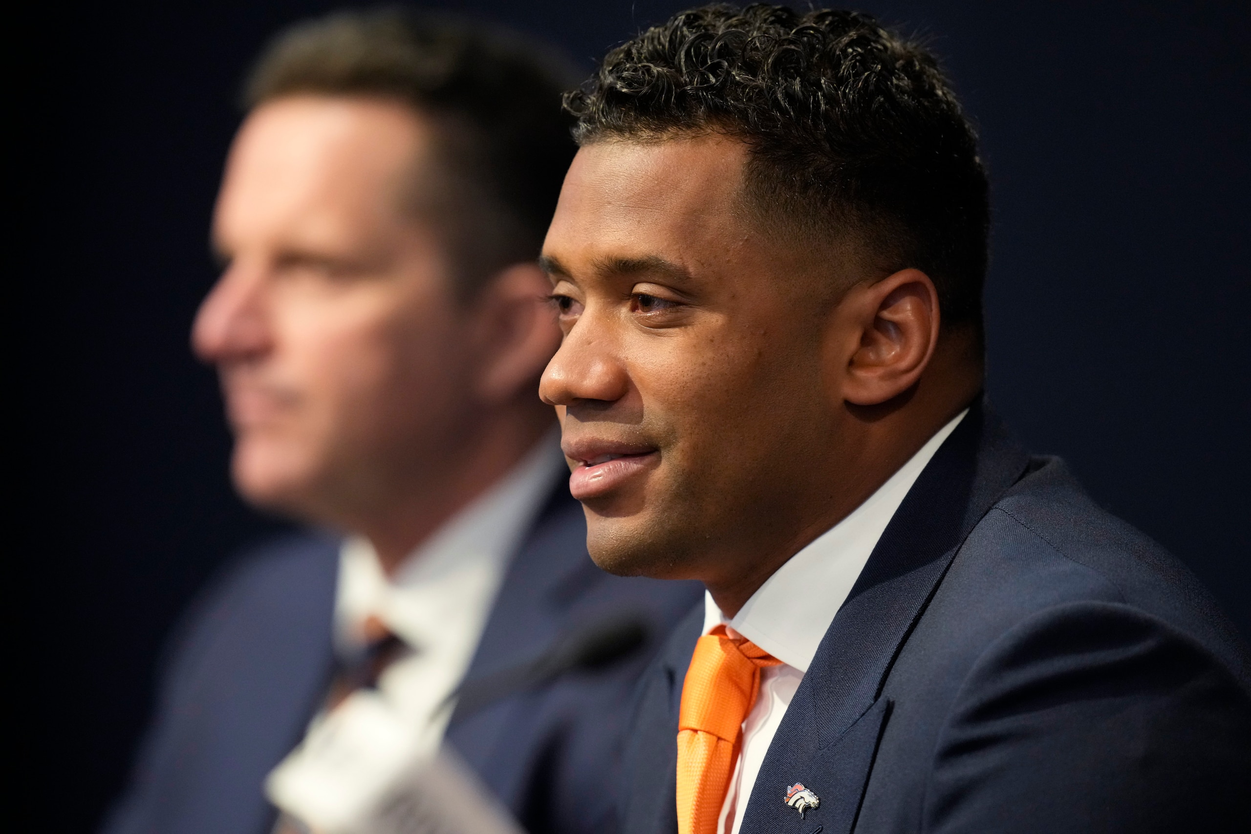 Denver Broncos new starting quarterback Russell Wilson listens to questioin as general manager George Paton looks on during a news conference Wednesday, March 16, 2022, at the team's headquarters in Englewood, Colo. (AP Photo/David Zalubowski)