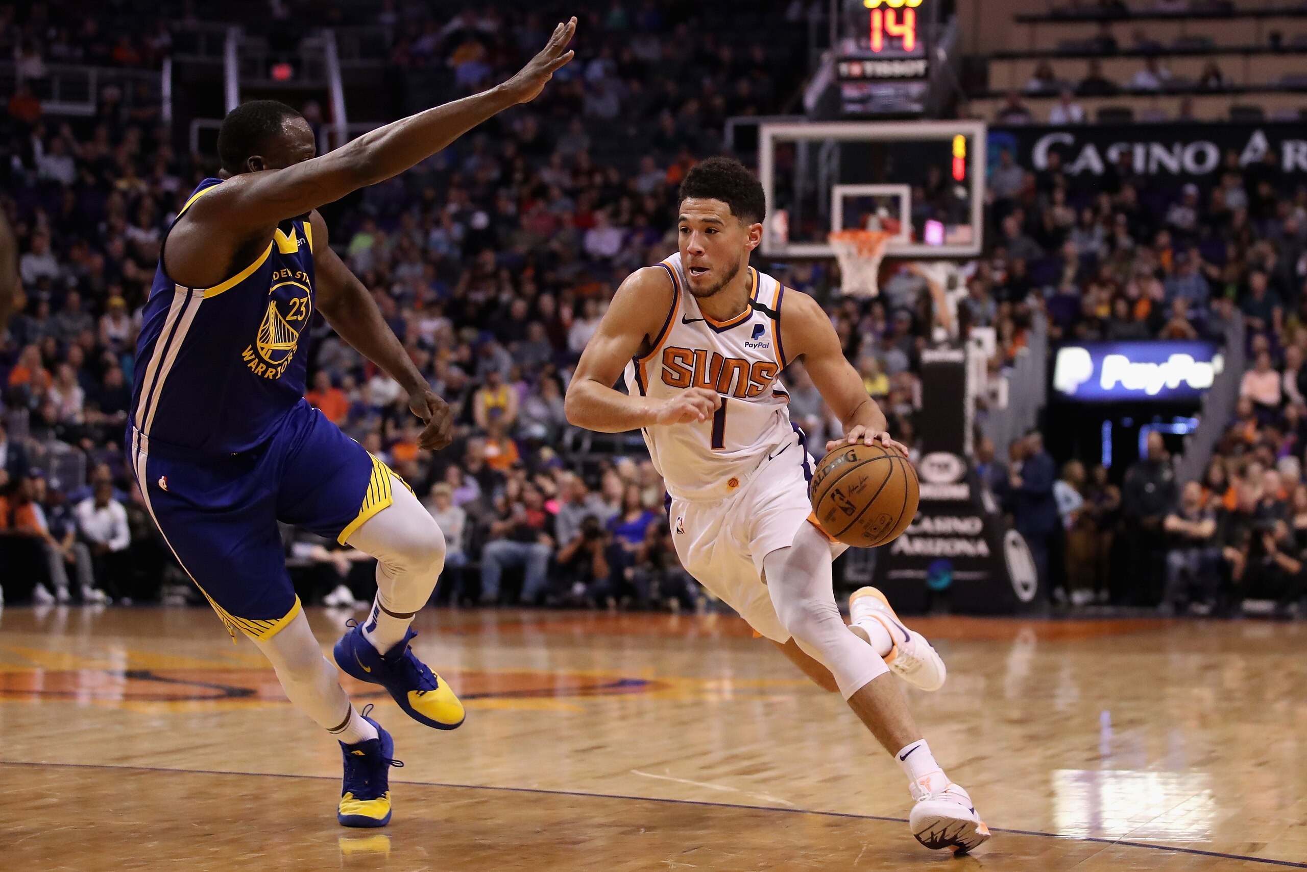 PHOENIX, ARIZONA - FEBRUARY 12:  Devin Booker #1 of the Phoenix Suns drives the ball past Draymond Green #23 of the Golden State Warriors during the second half of the NBA game at Talking Stick Resort Arena on February 12, 2020 in Phoenix, Arizona. The Suns defeated the Warriors 112-106. NOTE TO USER: User expressly acknowledges and agrees that, by downloading and or using this photograph, user is consenting to the terms and conditions of the Getty Images License Agreement. (Photo by Christian Petersen/Getty Images)