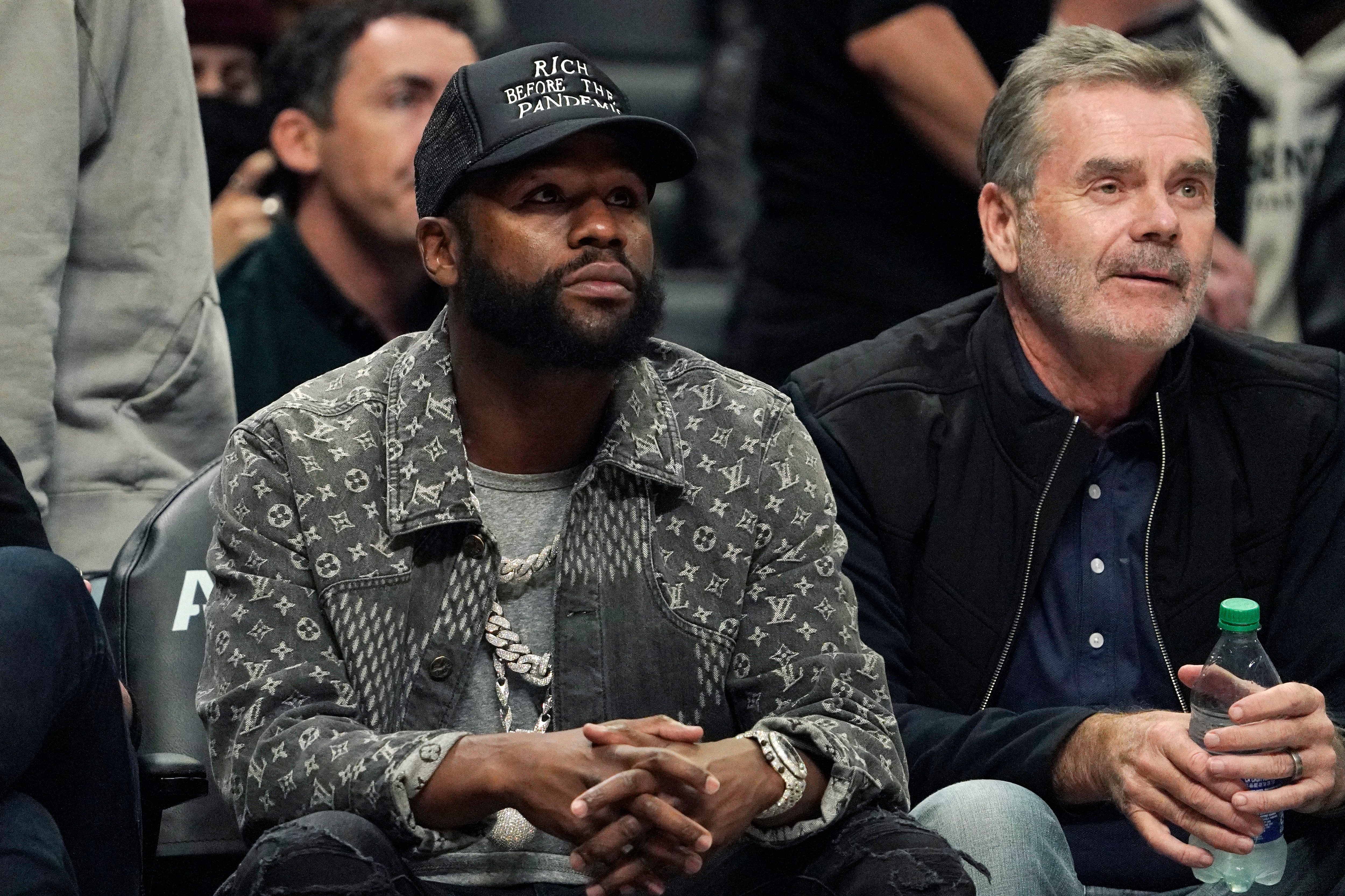 Boxer Floyd Mayweather Jr., left, watches during the second half of an NBA basketball game between the Los Angeles Clippers and the Sacramento Kings Wednesday, Dec. 1, 2021, in Los Angeles. (AP Photo/Mark J. Terrill)