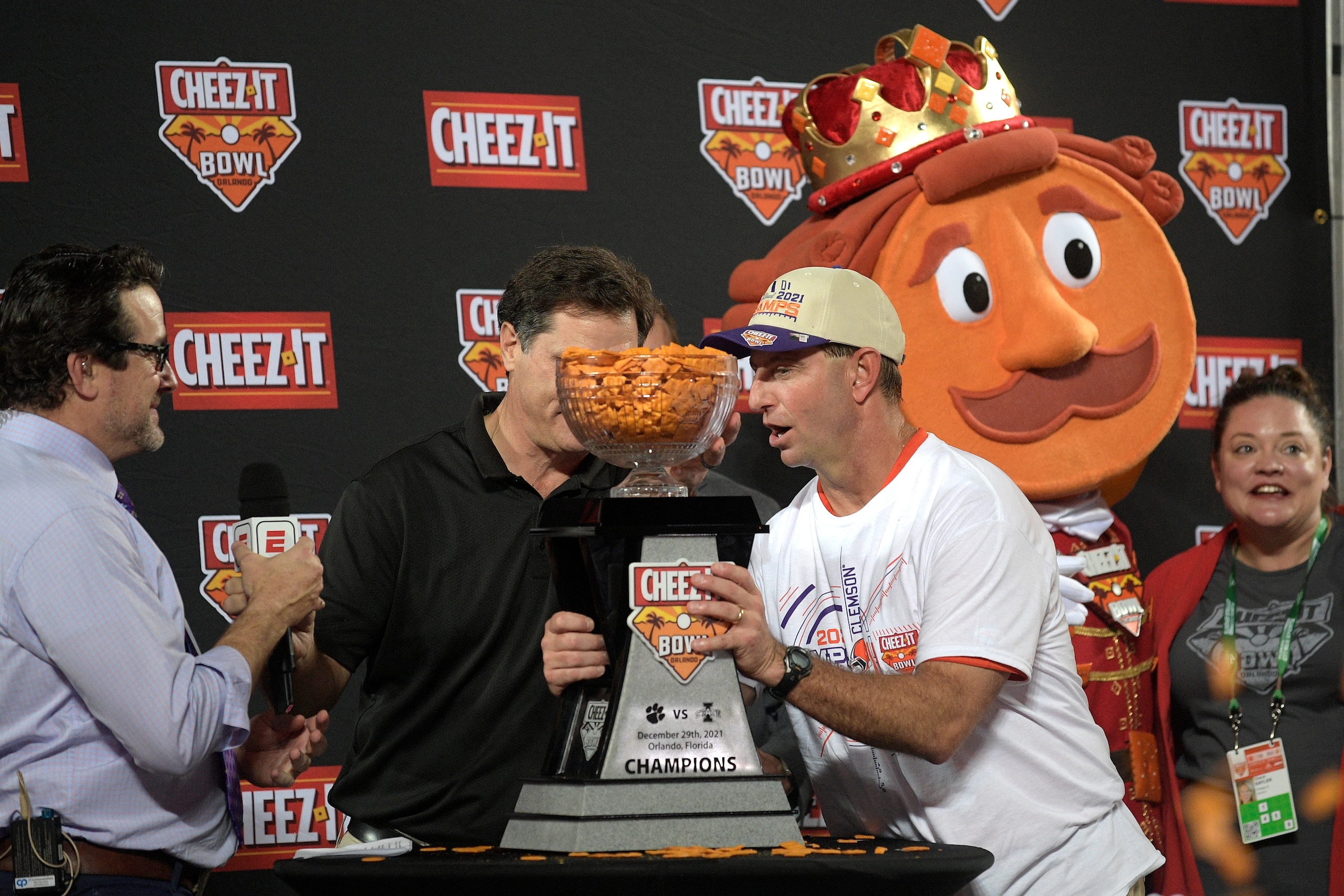 Clemson head coach Dabo Swinney, front right, is presented with the championship trophy after winning the Cheez-It Bowl NCAA college football game against Iowa State, Wednesday, Dec. 29, 2021, in Orlando, Fla. (AP Photo/Phelan M. Ebenhack)