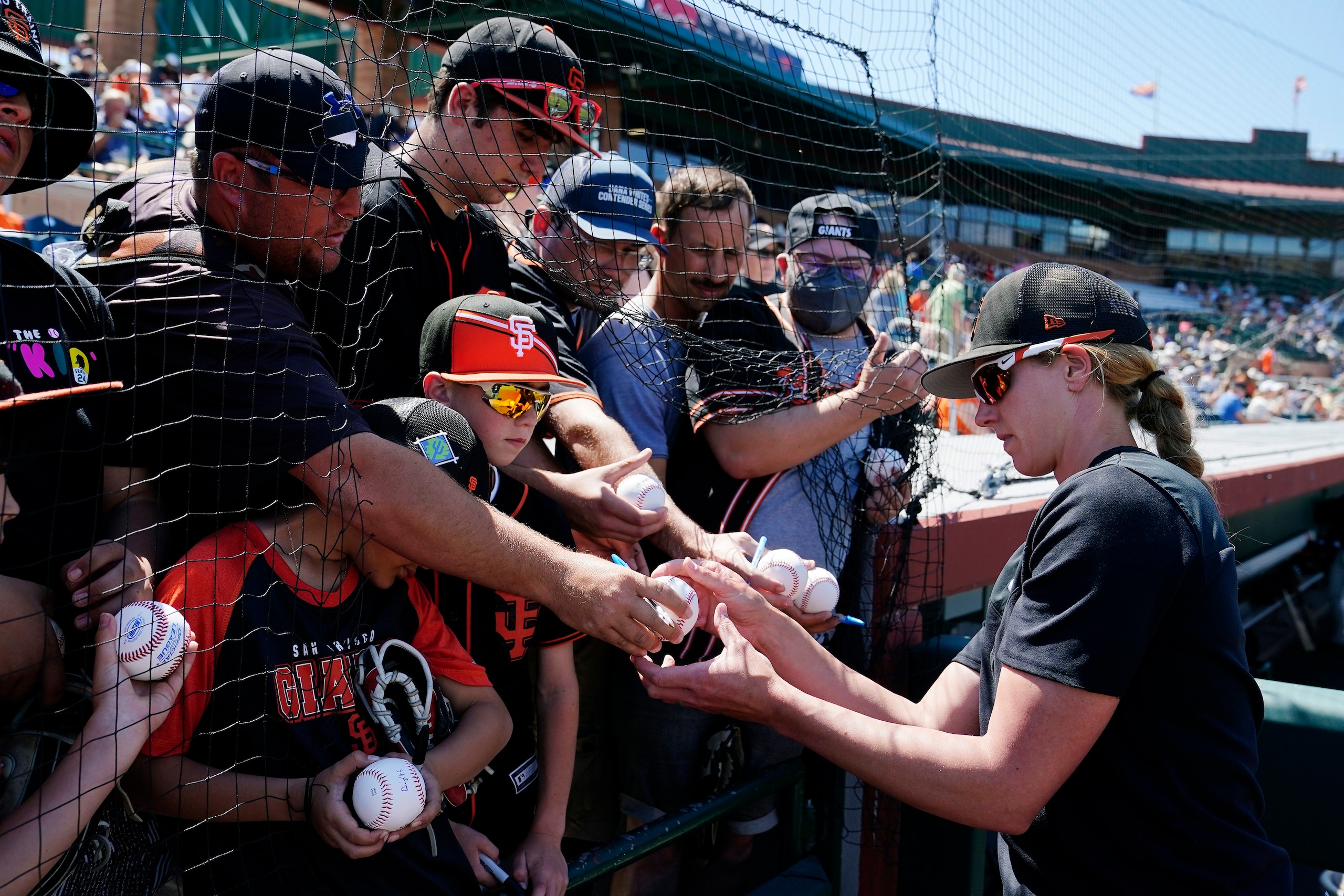 San Francisco Giants assistant coach Alyssa Nakken signs autographs for fans prior to a spring training baseball game against the Colorado Rockies Thursday, March 31, 2022, in Scottsdale, Ariz. (AP Photo/Ross D. Franklin)