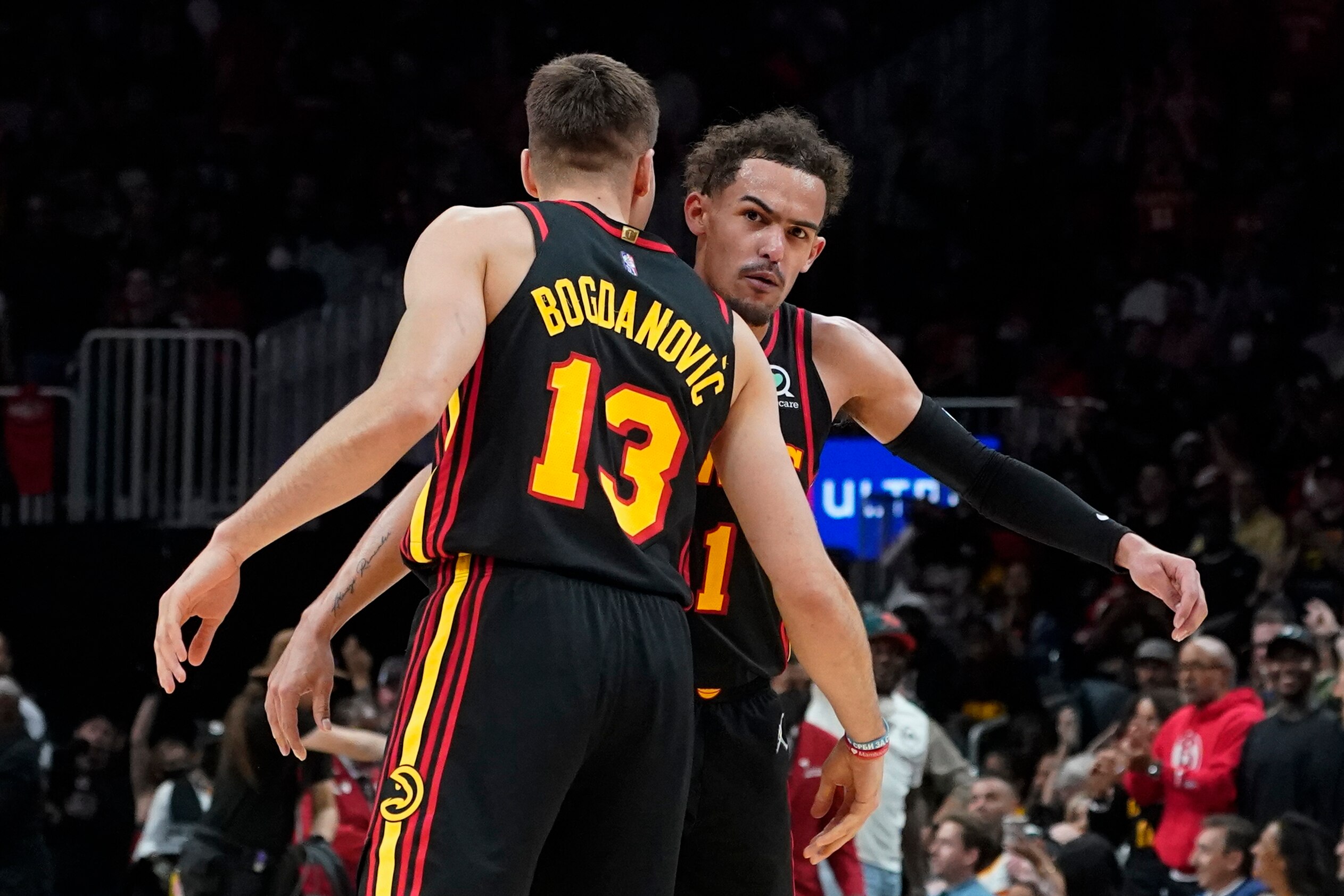 Atlanta Hawks guards Trae Young and Bogdan Bogdanovic (13) celebrate after a Hawks basket during the second half of the team's NBA play-in basketball game against the Charlotte Hornets on Wednesday, April 13, 2022, in Atlanta. (AP Photo/John Bazemore)