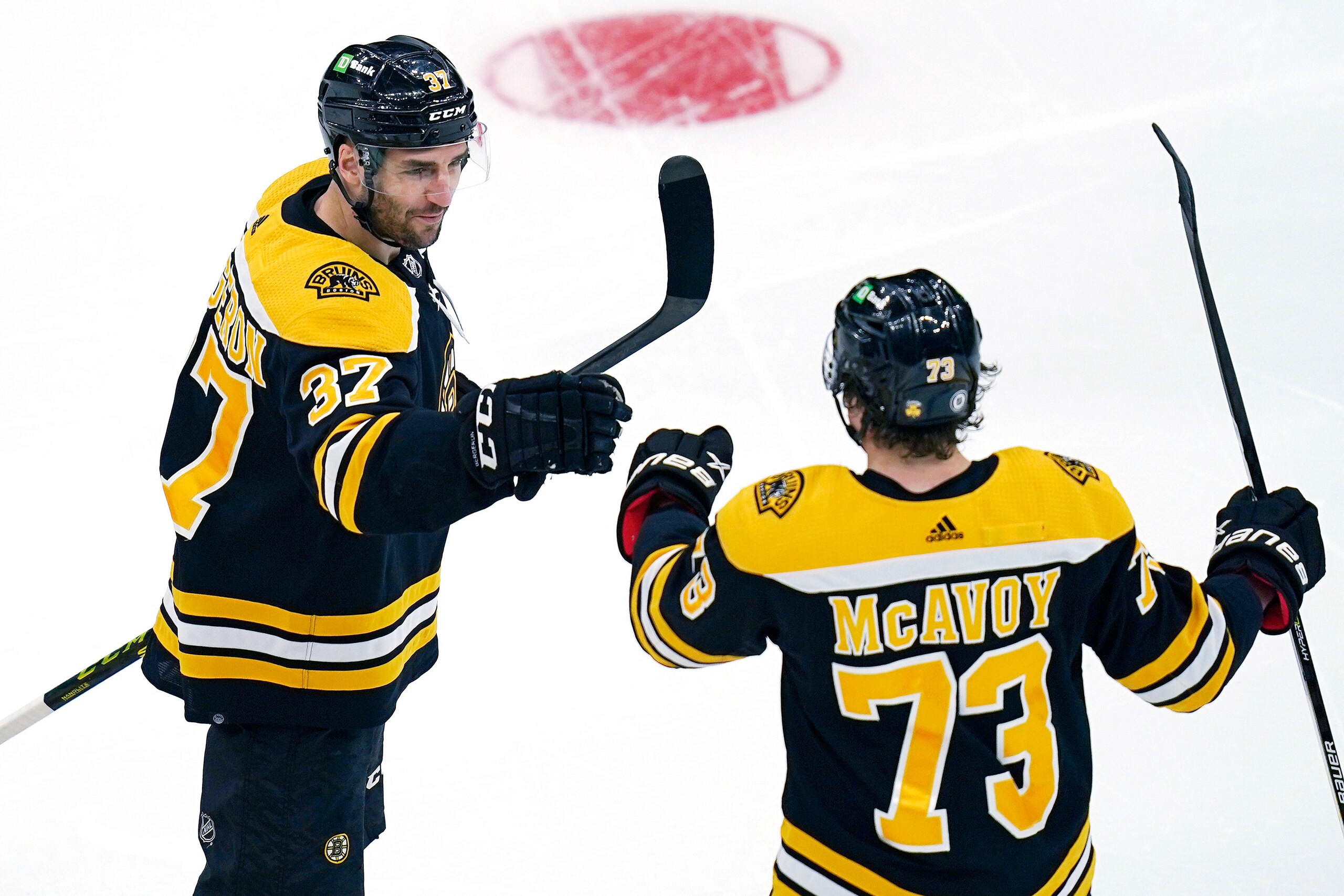 Boston Bruins center Patrice Bergeron (37) is congratulated by Charlie McAvoy after his goal during the first period of an NHL hockey game against the St. Louis Blues, Tuesday, April 12, 2022, in Boston. (AP Photo/Charles Krupa)