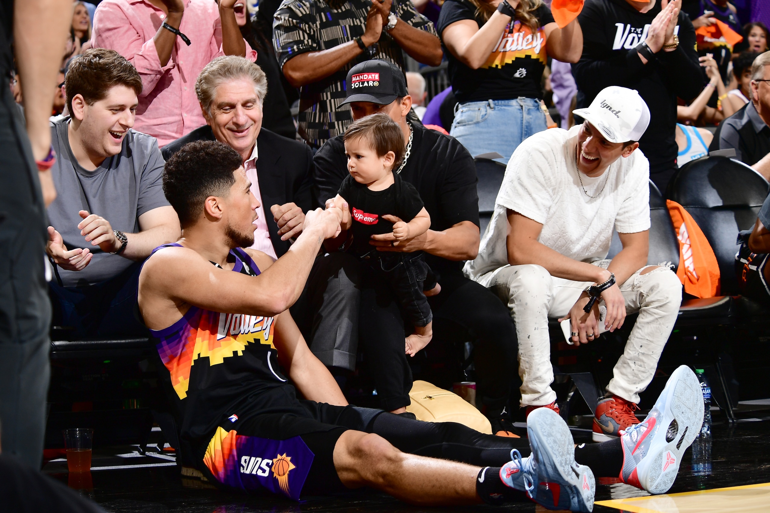 PHOENIX, AZ - APRIL 19:  Devin Booker #1 of the Phoenix Suns high fives a fan during Round 1 Game 2 of the 2022 NBA Playoffs on April 19, 2022 at Footprint Center in Phoenix, Arizona. NOTE TO USER: User expressly acknowledges and agrees that, by downloading and or using this photograph, user is consenting to the terms and conditions of the Getty Images License Agreement. Mandatory Copyright Notice: Copyright 2022 NBAE (Photo by Michael Gonzales/NBAE via Getty Images)