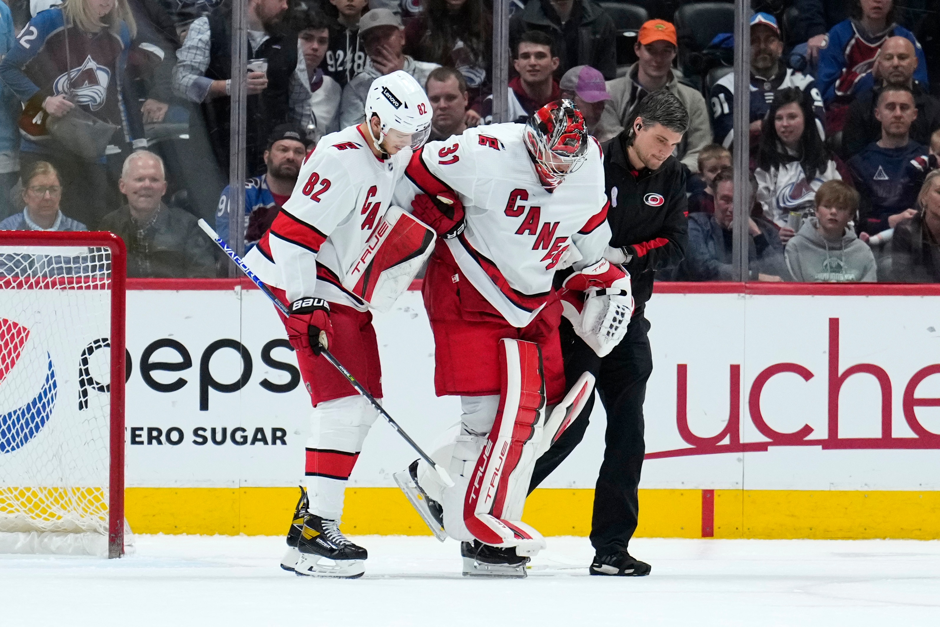 Carolina Hurricanes goaltender Frederik Andersen (31) is helped off the ice by Jesperi Kotkaniemi (82) and a trainer during the third period of the team's NHL hockey game against the Colorado Avalanche on Saturday, April 16, 2022, in Denver. (AP Photo/Jack Dempsey)