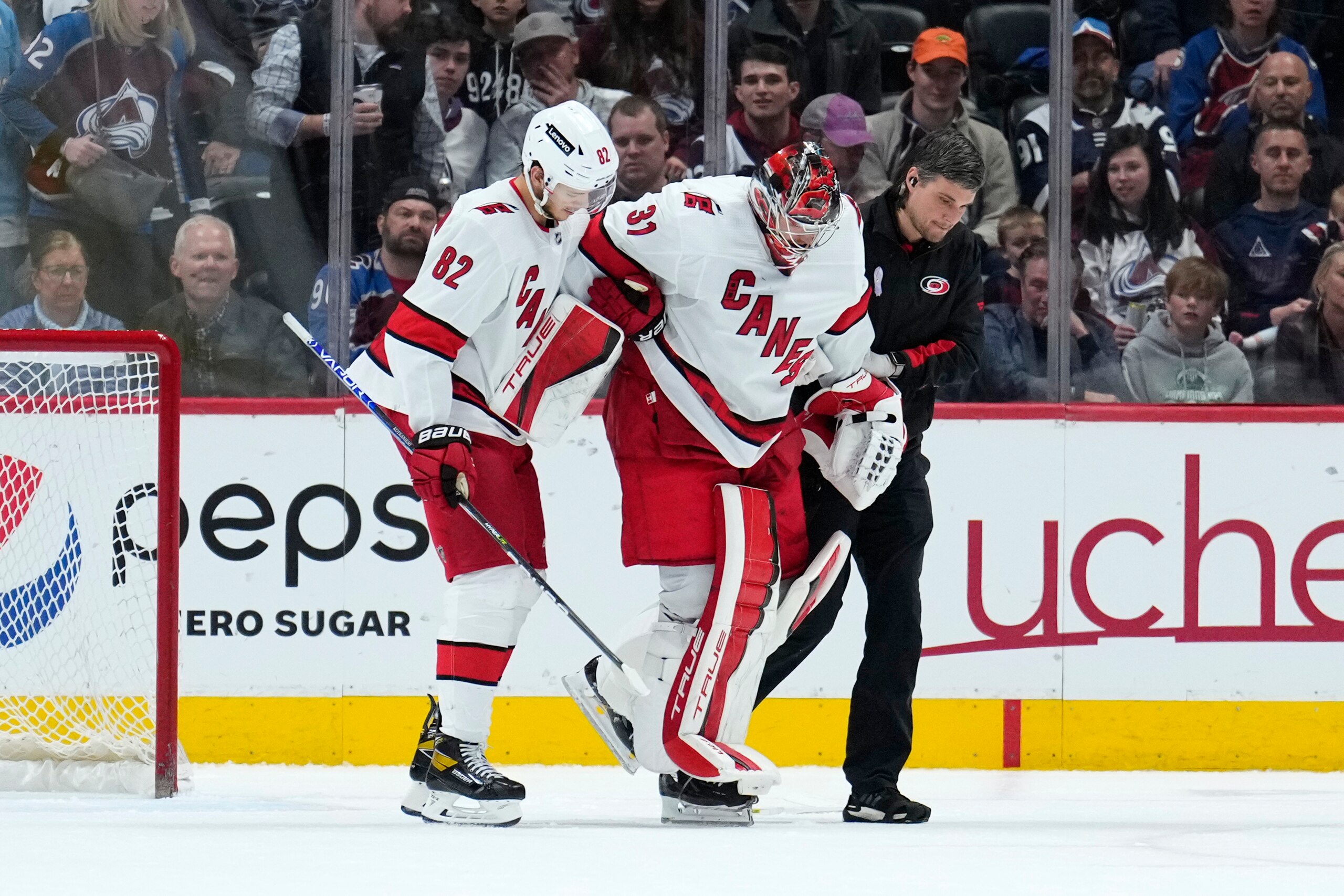 Carolina Hurricanes goaltender Frederik Andersen (31) is helped off the ice by Jesperi Kotkaniemi (82) and a trainer during the third period of the team's NHL hockey game against the Colorado Avalanche on Saturday, April 16, 2022, in Denver. (AP Photo/Jack Dempsey)