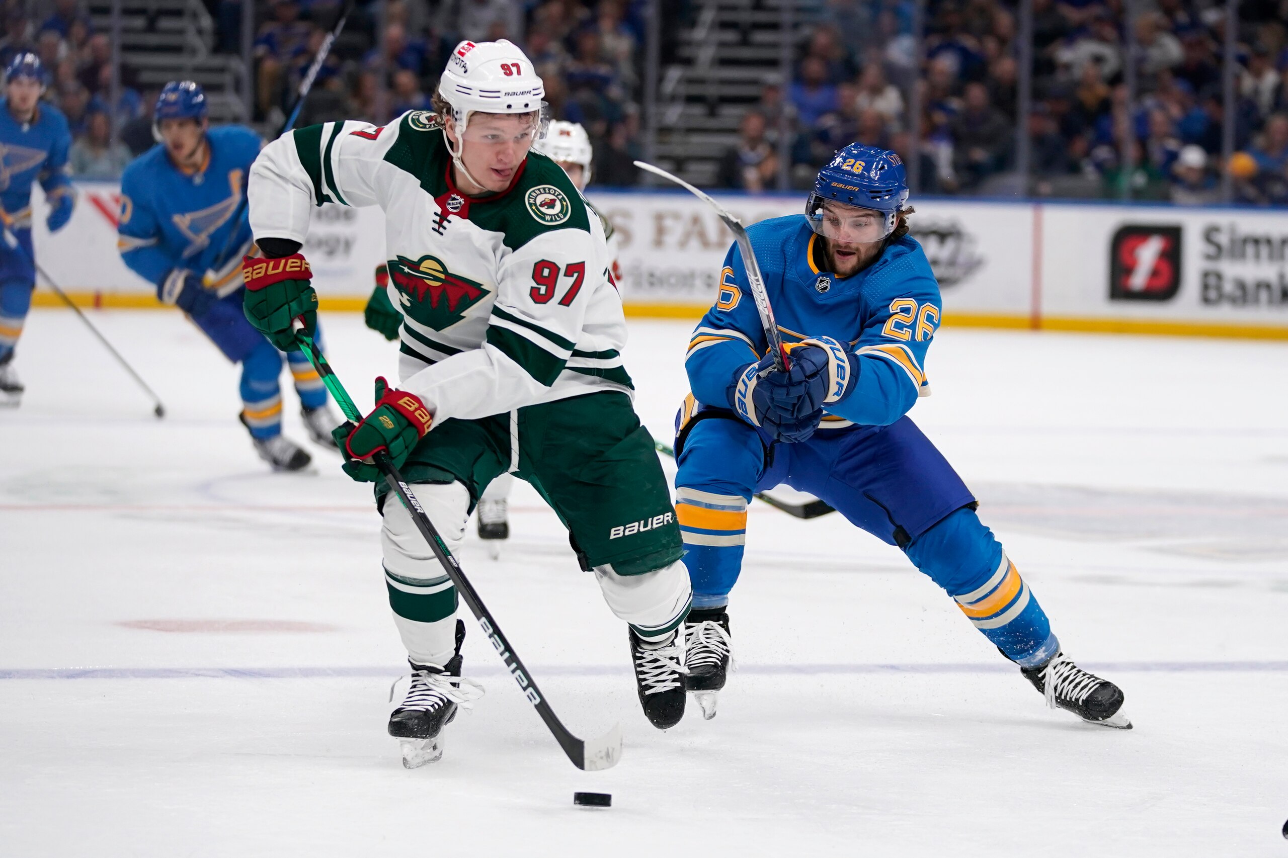 Minnesota Wild's Kirill Kaprizov (97) brings the puck down the ice as St. Louis Blues' Nathan Walker (26) defends during the first period of an NHL hockey game Saturday, April 16, 2022, in St. Louis. (AP Photo/Jeff Roberson)