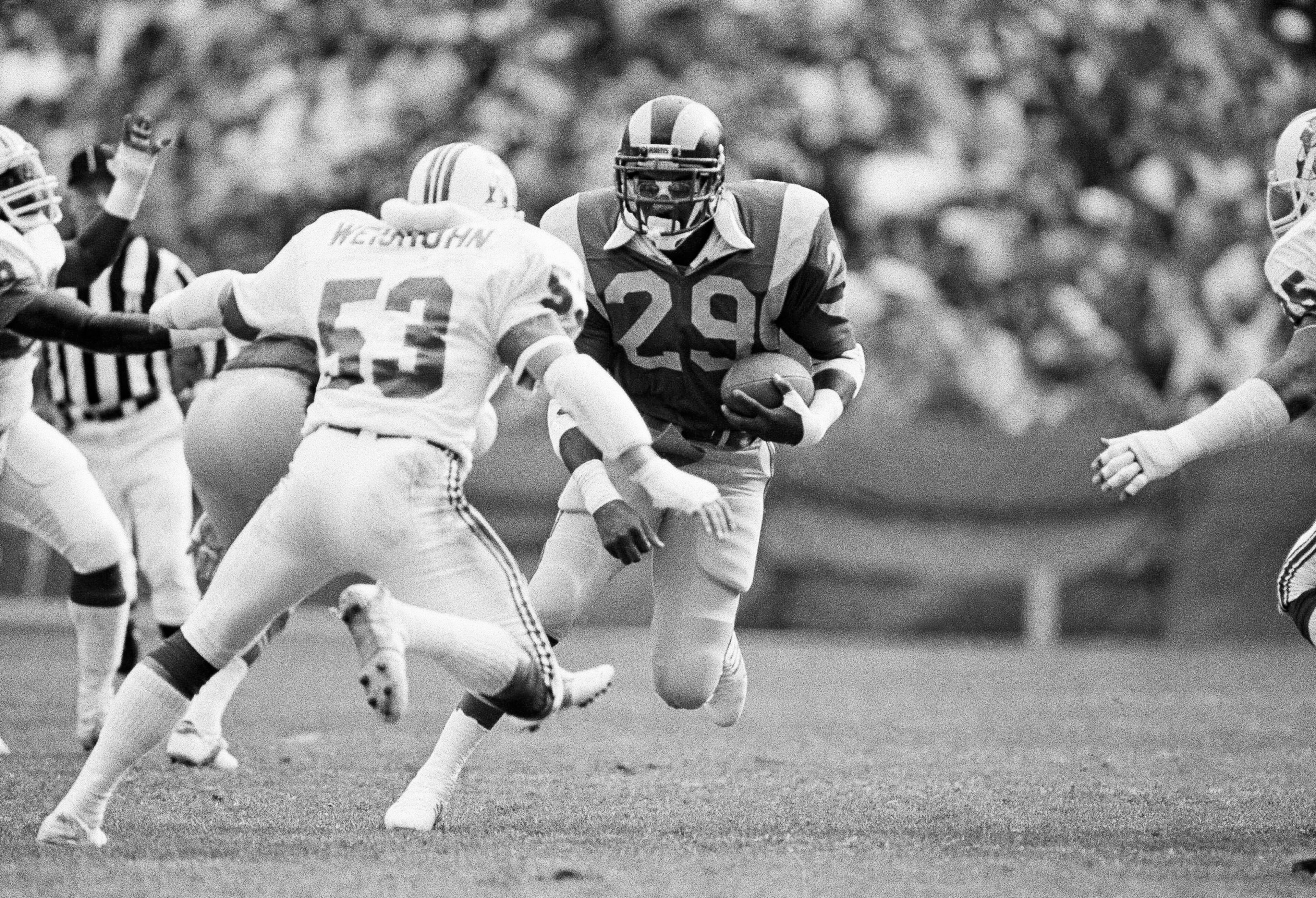 Los Angeles Rams halfback Eric Dickerson confronts New England Patriots linebacker Clayton Weishuhn in the first quarter at Anaheim Stadium on Sunday, Dec. 11, 1983 for an eight yard gain. Dickerson, with 94 yards in 27 carries, became the top ground-gaining first-year player in the NFLโs history by topping the 1,674 yards picked up by New Orleans George Rogers in 1981. (AP Photo/Doug Pizac) Los Angeles Rams halfback Eric Dickerson confronts New England Patriots linebacker Clayton Weishuhn in the first quarter at Anaheim Stadium on Sunday, Dec. 11, 1983 for an eight yard gain. Dickerson, with 94 yards in 27 carries, became the top ground-gaining first-year player in the NFLโs history by topping the 1,674 yards picked up by New Orleans George Rogers in 1981. (AP Photo/Doug Pizac)